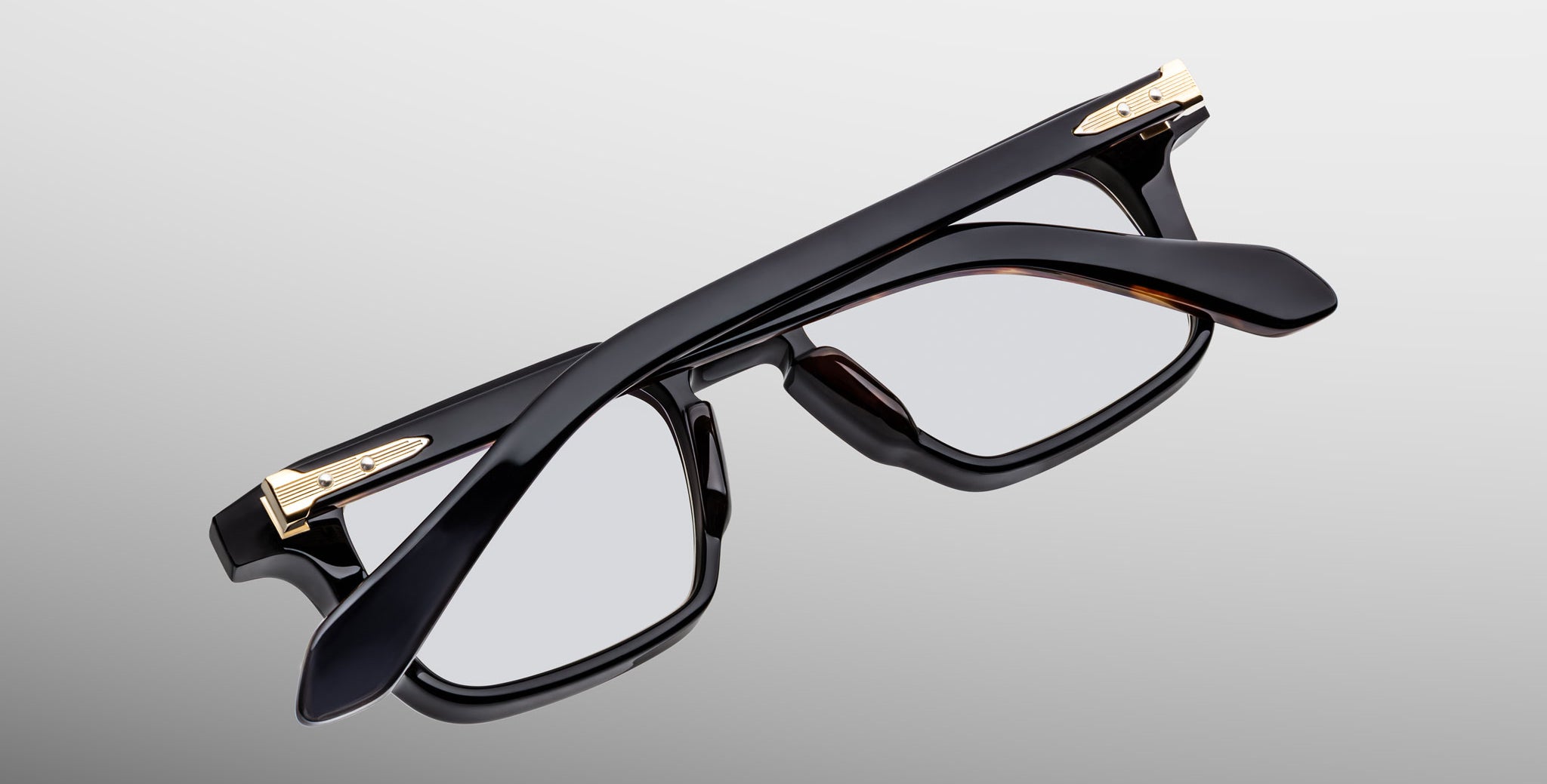 Jacques Marie Mage Moscova in Noir 15 acetate optical frame, top-down angled view showcasing bold rectangular silhouette, polished black acetate, arrowhead front pins, and gold monoblock hinges with sculpted temples