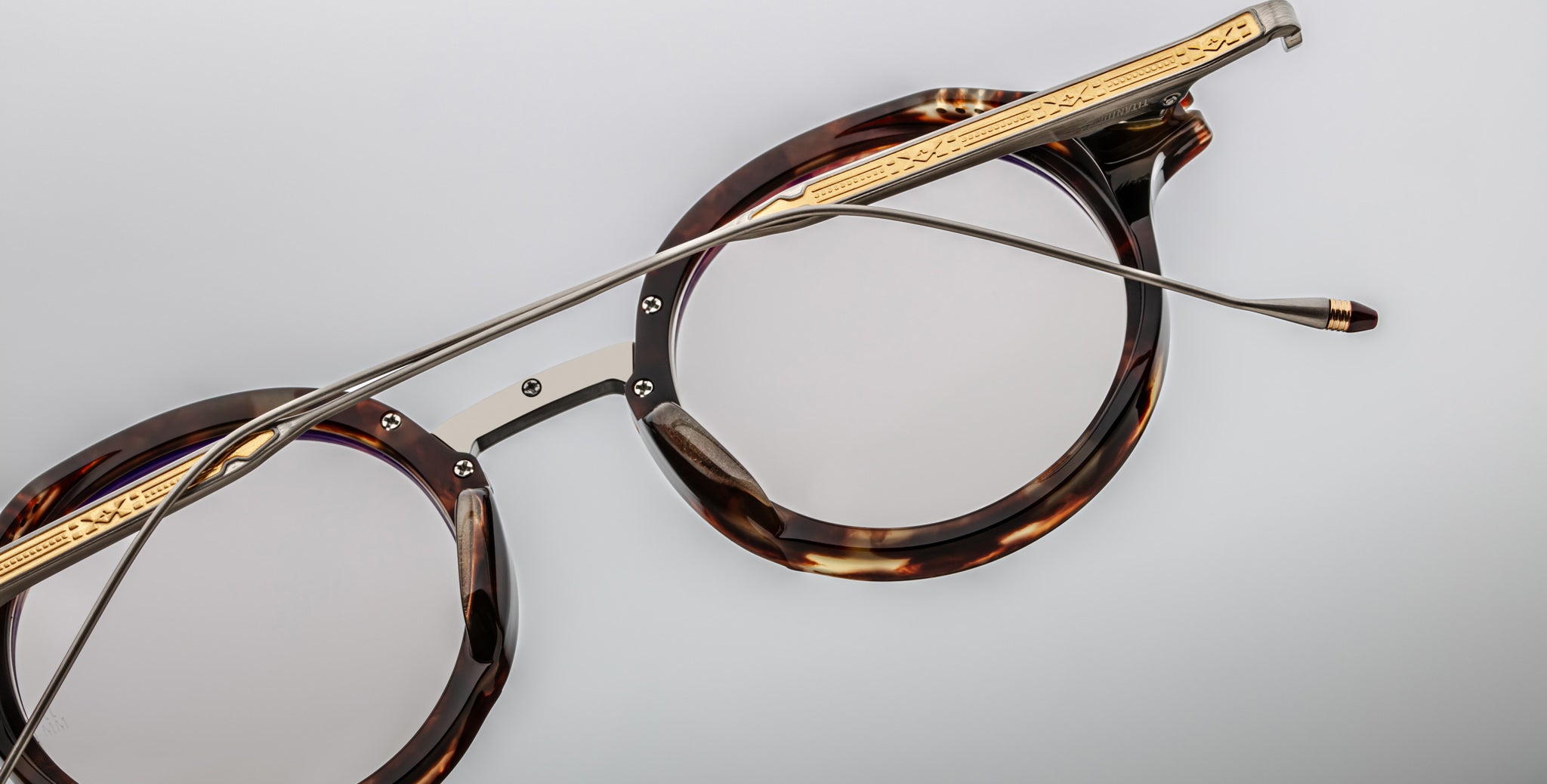 Jacques Marie Mage Norman round tortoiseshell eyeglasses with gold accents and slim metal arms, shown from a front angle.
