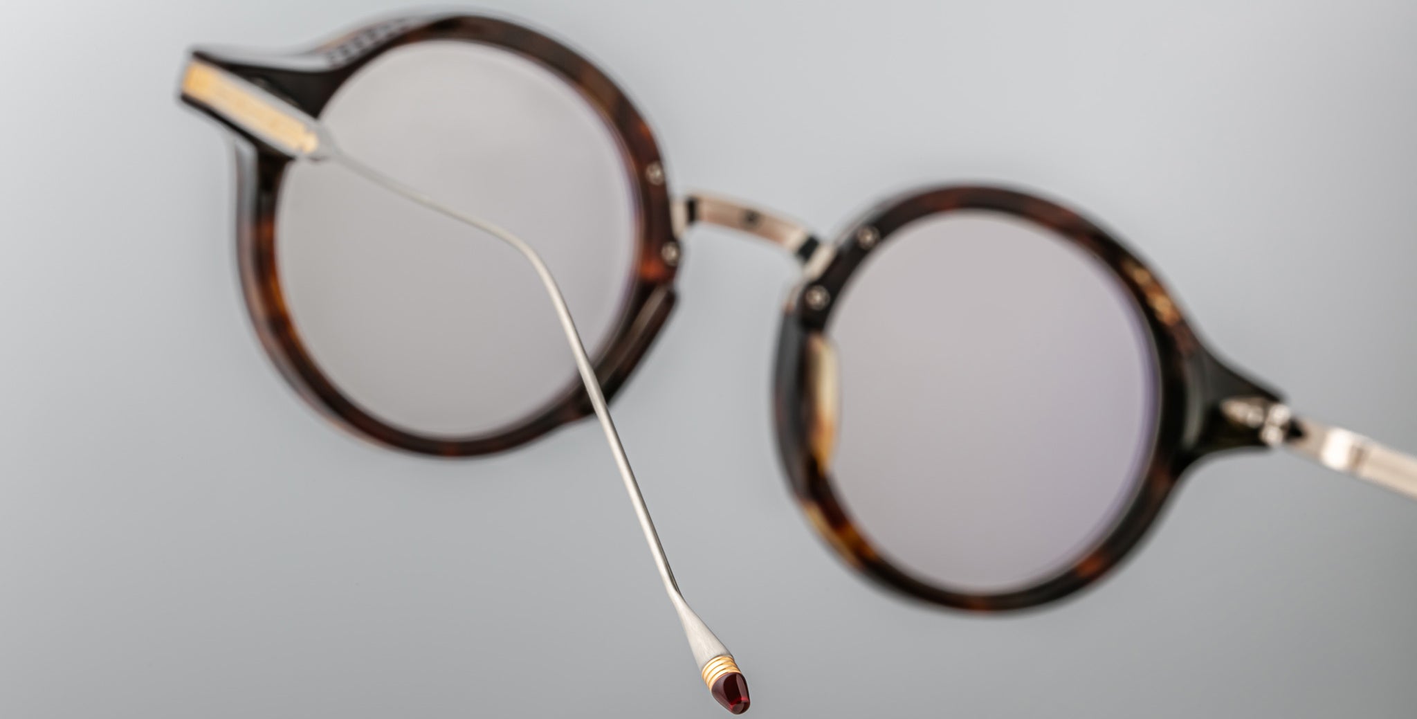 Jacques Marie Mage Norman eyeglasses, round tortoiseshell frames with thin metal arms and red tips, front view.