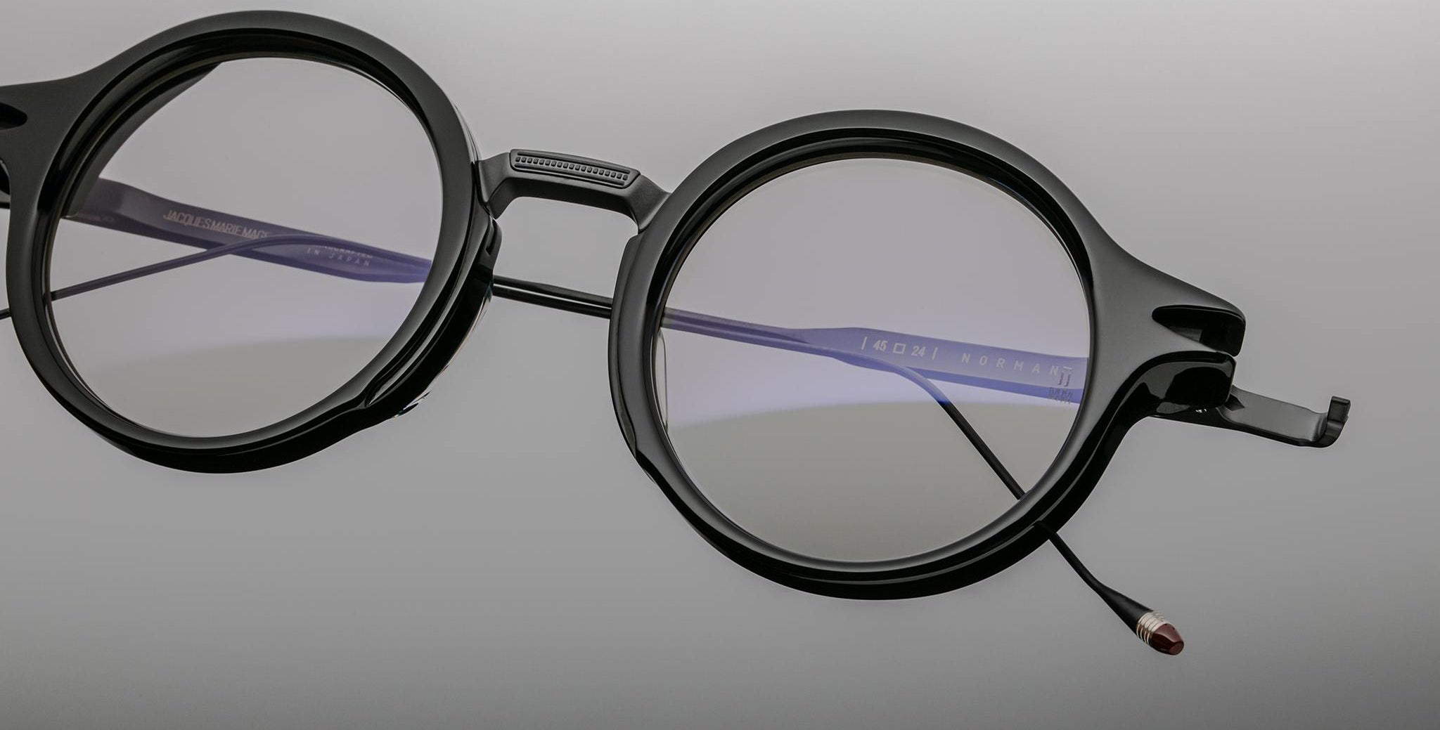 Jacques Marie Mage Norman round black eyeglasses with thick frames and one detached temple arm, front angle view.