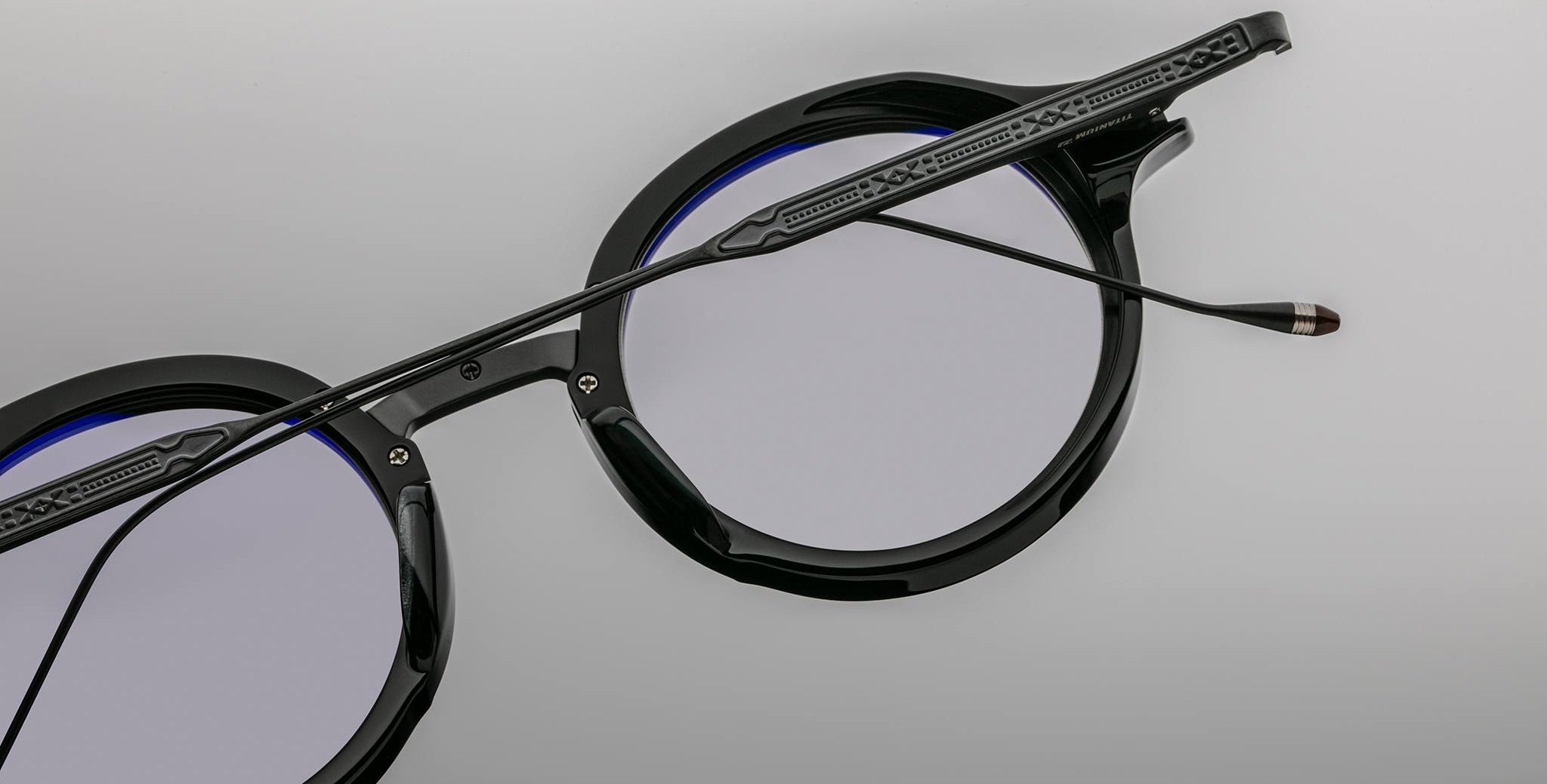 Close-up of Jacques Marie Mage Norman black round eyeglasses with blue-tinted, anti-glare lenses, front angle.