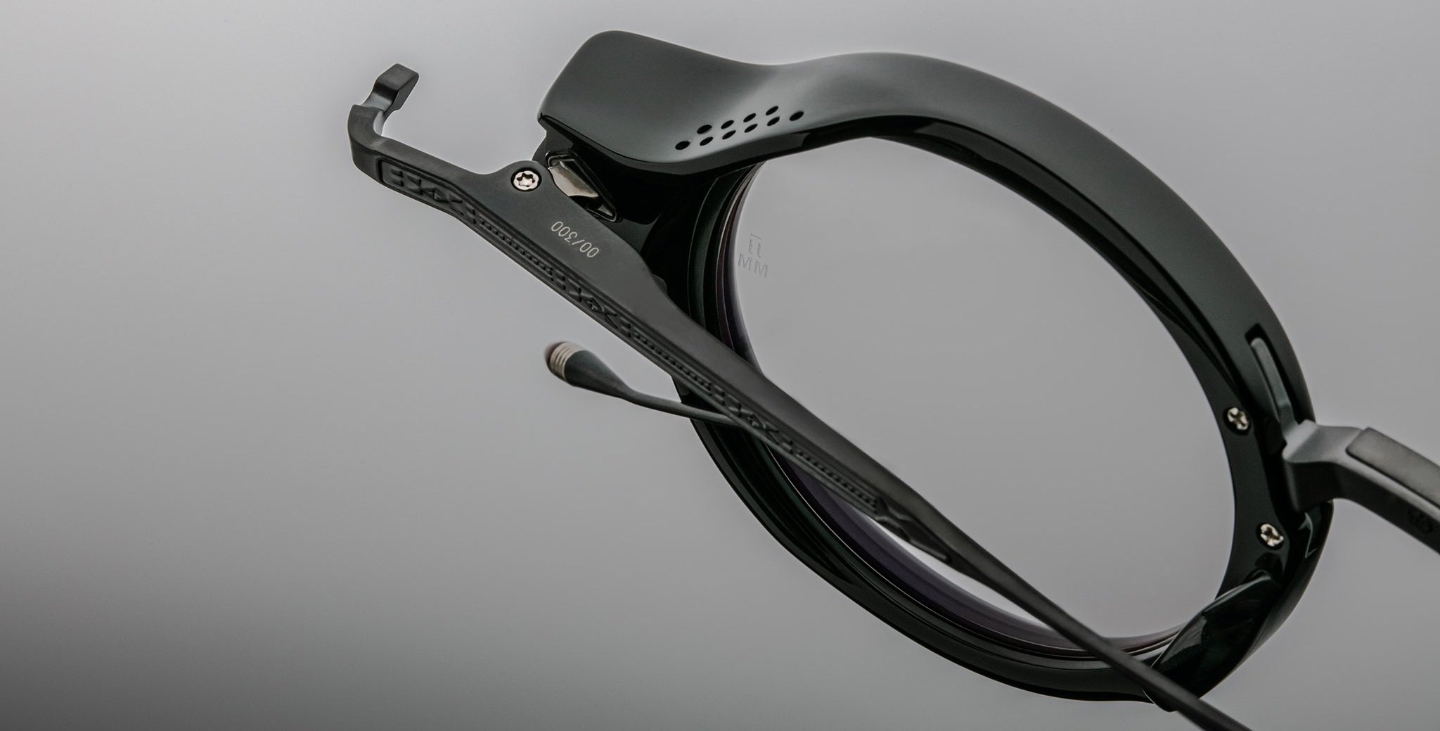 Close-up of Jacques Marie Mage Norman black smart eyeglasses, showing Bluetooth mic and speaker on the temple.