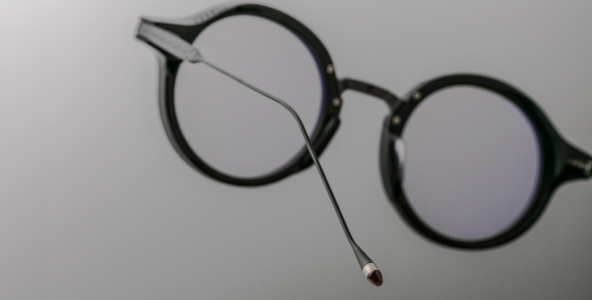 Close-up of Jacques Marie Mage Norman black round eyeglasses, side angle showing one temple arm extended.