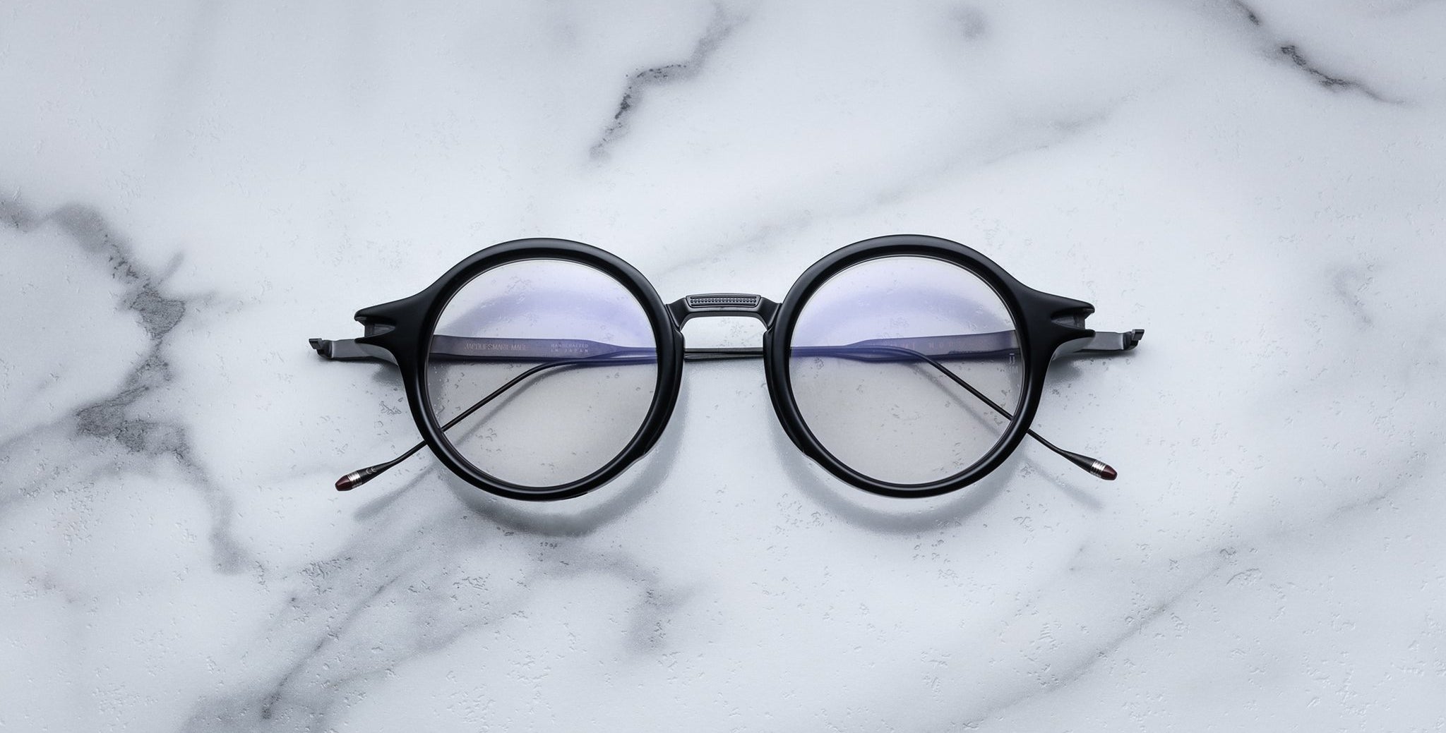 Jacques Marie Mage Norman round black eyeglasses with clear lenses, front view.