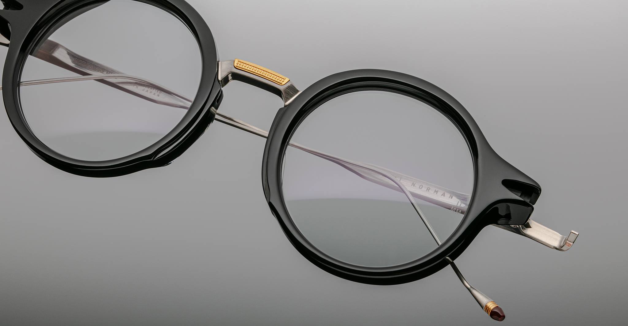 Jacques Marie Mage Norman round black eyeglasses with metal bridge and temples, close-up angle.