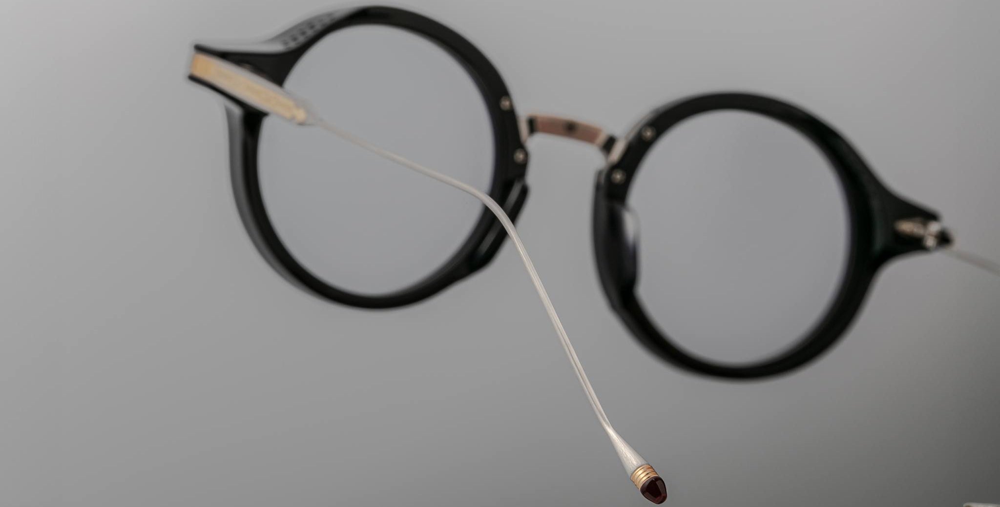 Jacques Marie Mage Norman eyeglasses, round black frames with a slim silver nose bridge, front view.