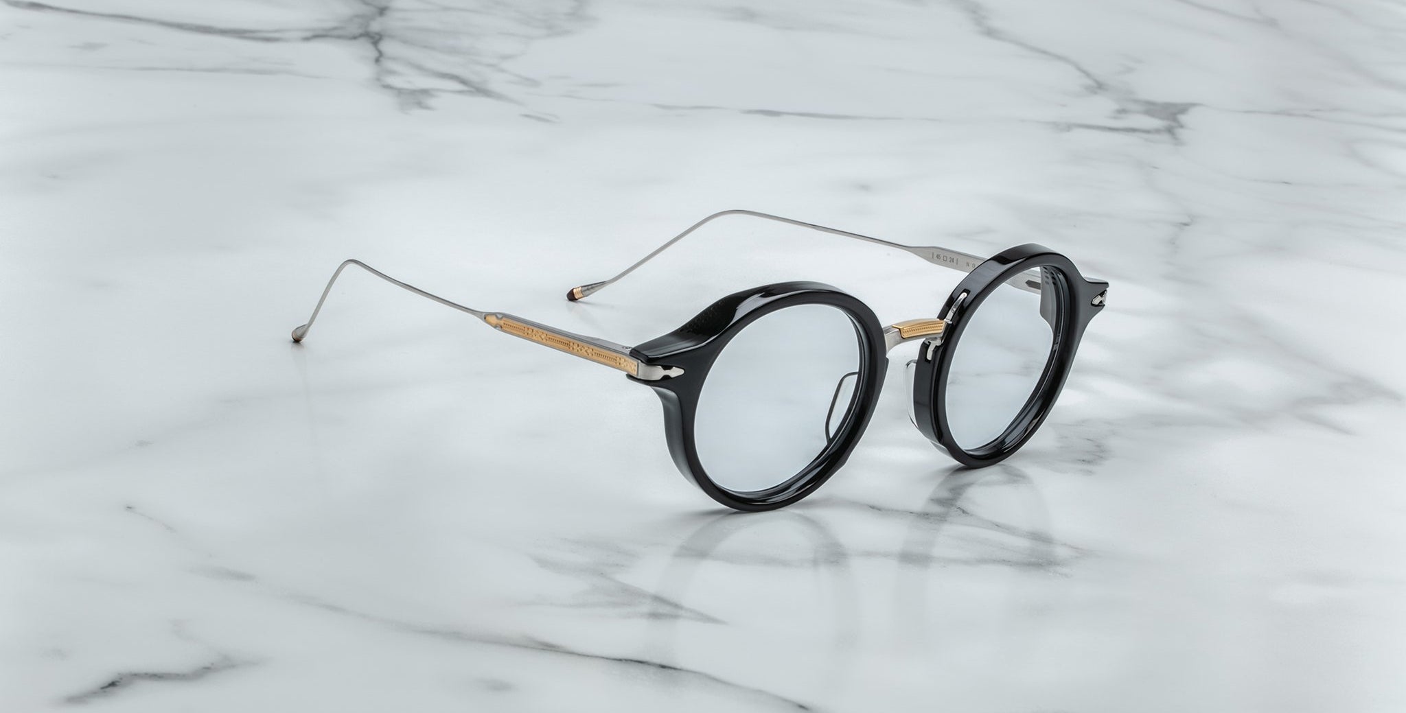 Jacques Marie Mage Norman eyeglasses with round black rims and thin metal arms, front angle.