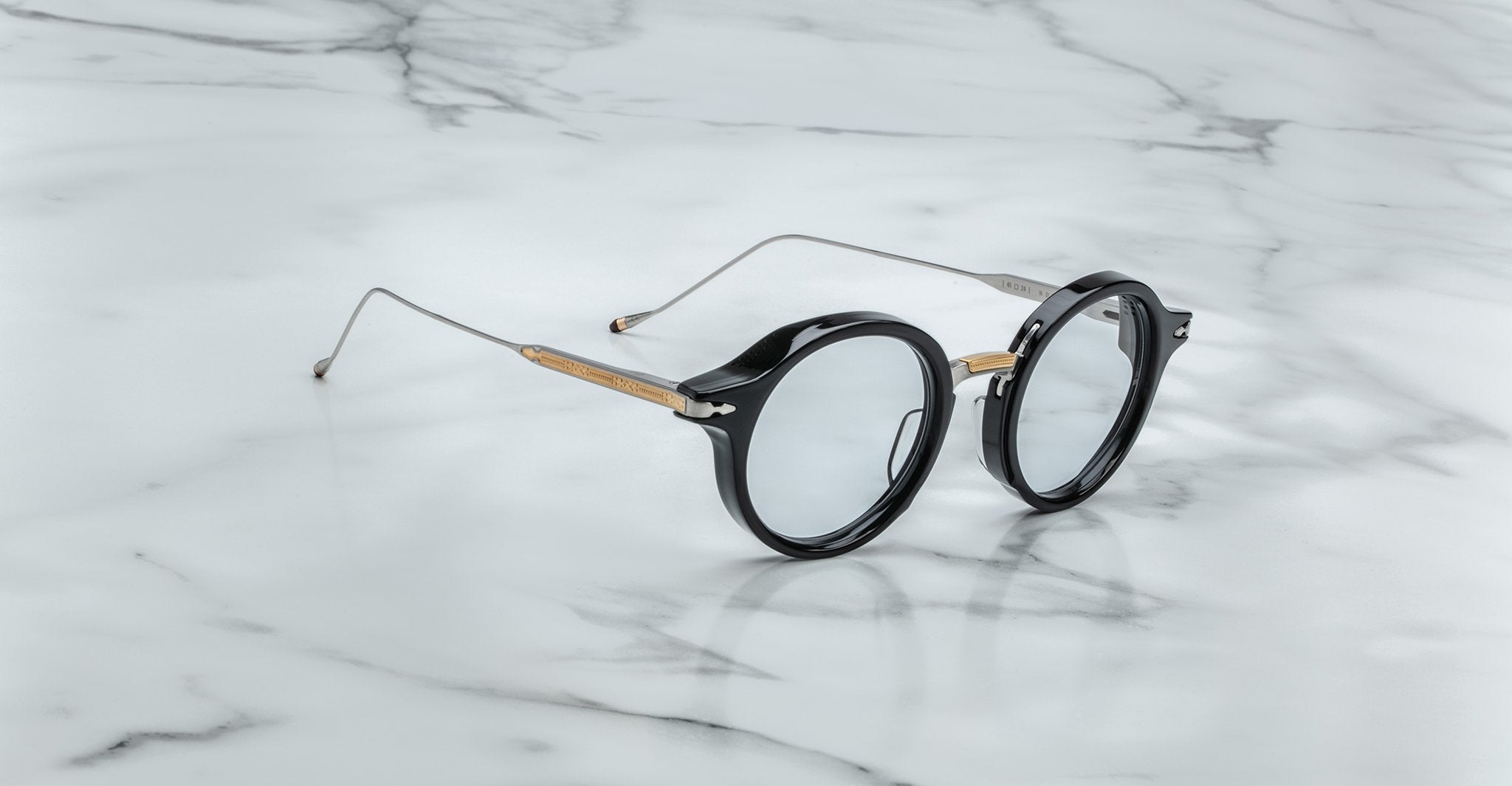 Jacques Marie Mage Norman eyeglasses with round black rims and thin metal arms, front angle.