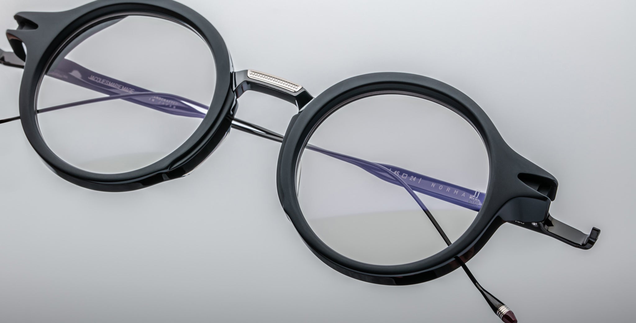 Jacques Marie Mage Norman round black eyeglasses with clear lenses and thin temples shown from above.