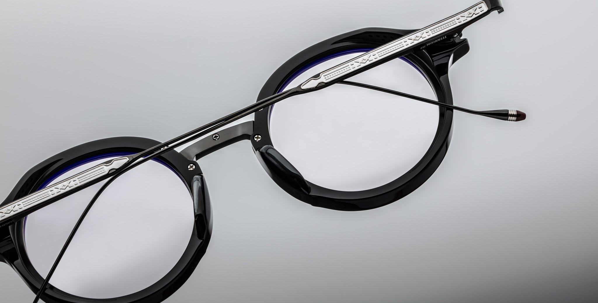 Close-up of Jacques Marie Mage Norman round eyeglasses in black with silver arms, showing front and side details.
