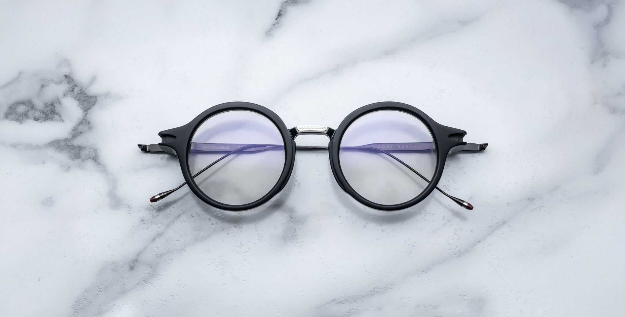 Jacques Marie Mage Norman black eyeglasses with clear lenses, shown from above.