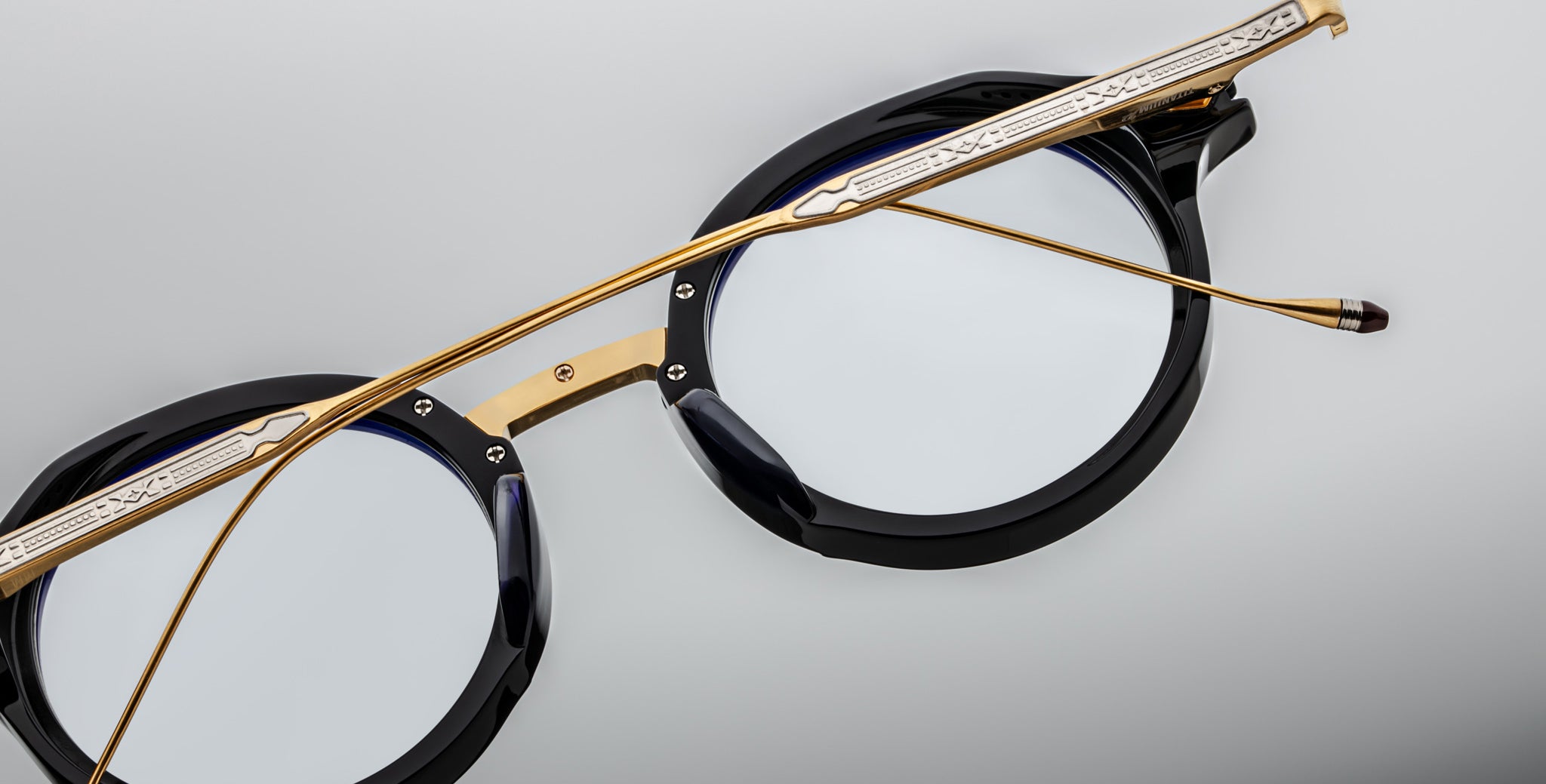 Jacques Marie Mage Norman eyeglasses, black round frames, gold metal temples, clear lenses, shown from the front angle.