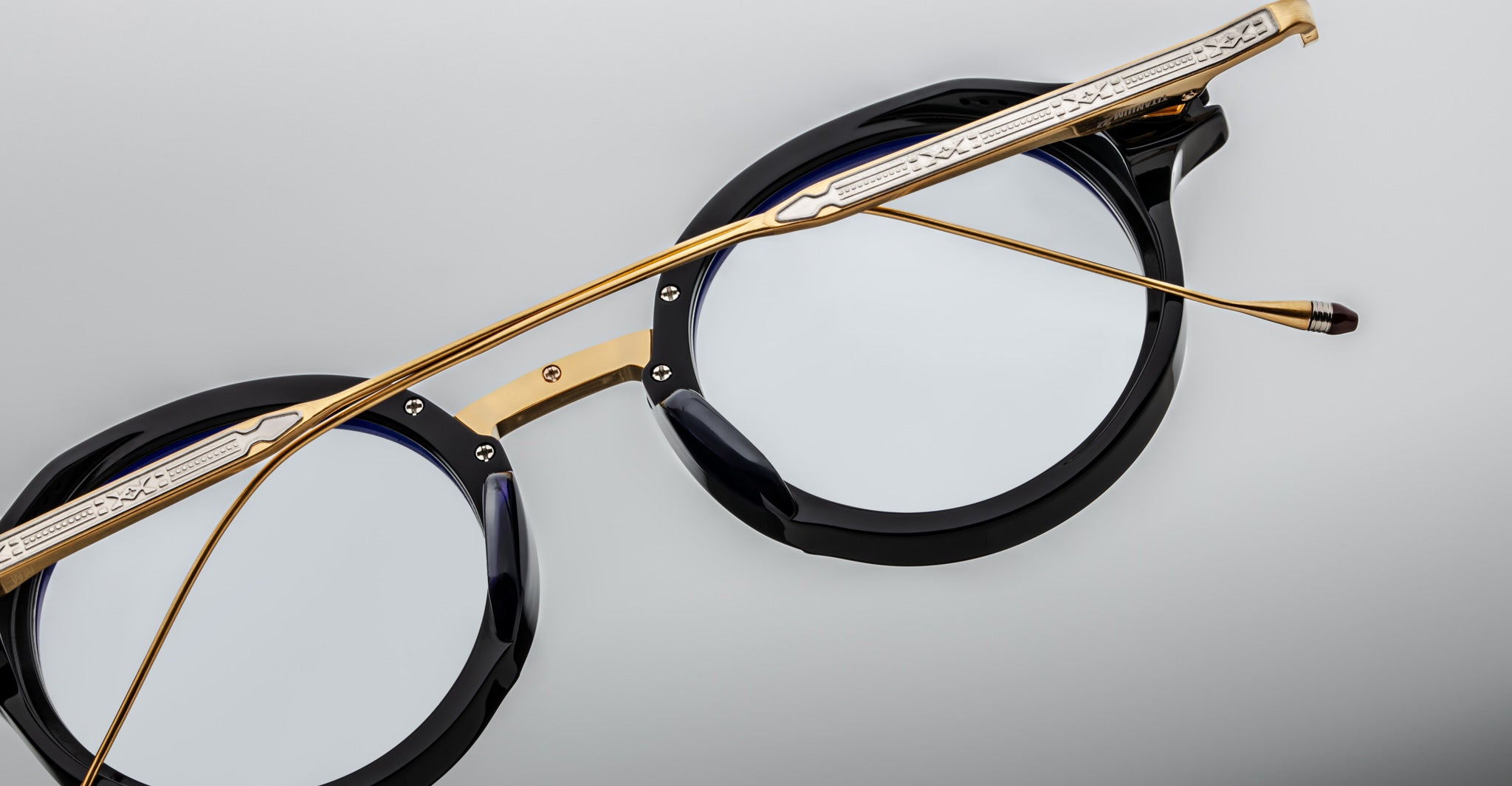 Jacques Marie Mage Norman eyeglasses, black round frames, gold metal temples, clear lenses, shown from the front angle.