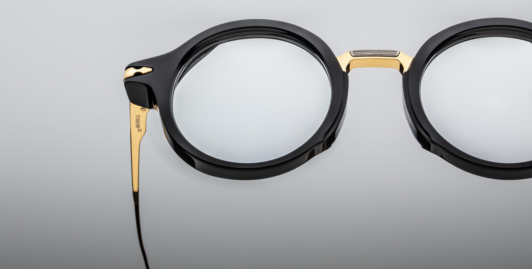 Close-up of Jacques Marie Mage Norman eyeglasses, black and gold, thick frames, slim metal temple wire, front angle view.