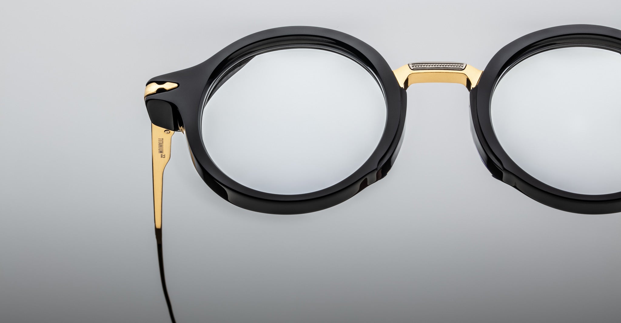 Close-up of Jacques Marie Mage Norman eyeglasses, black and gold, thick frames, slim metal temple wire, front angle view.