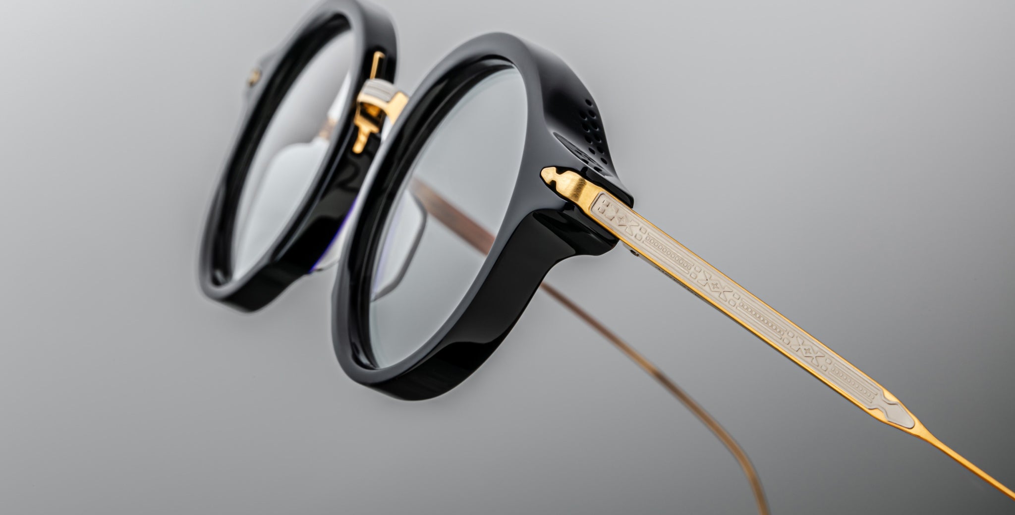 Close-up of Jacques Marie Mage Norman round eyeglasses, black frame with gold temples, front angle.