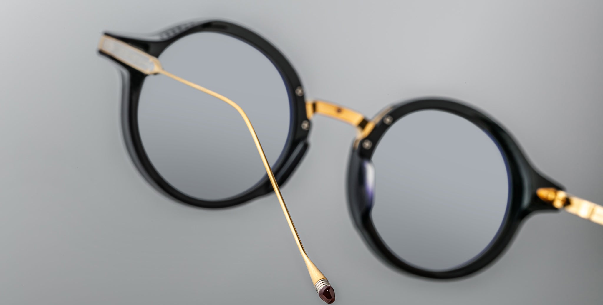 Jacques Marie Mage Norman round black eyeglasses with gold temples, side view showing end tip detail.