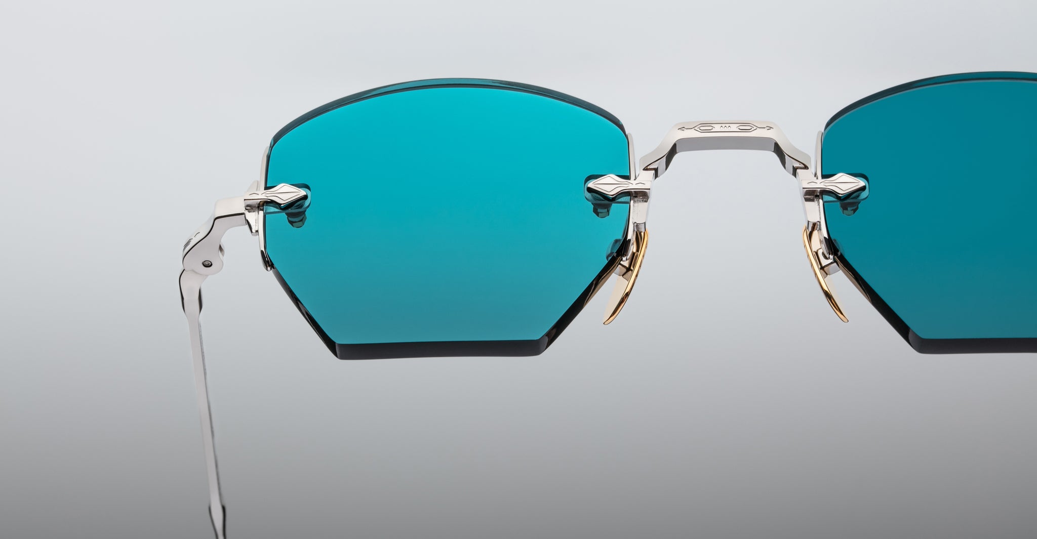 Close-up of Jacques Marie Mage Oatman eyewear: blue-tinted, angular lenses and metallic frames, inspired by signature Jacques Marie Mage design, displayed on a neutral background.