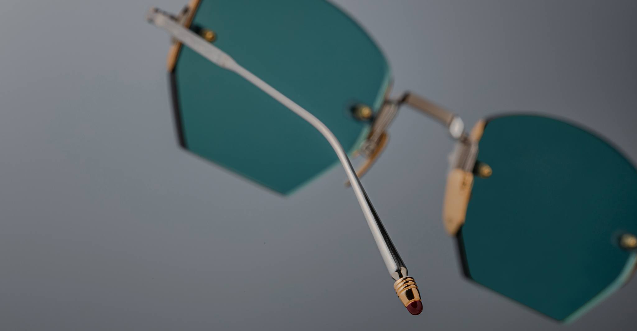 Close-up of Jacques Marie Mage Oatman teal hexagonal eyeglasses with gold accents, highlighting the bent arm and temple tip—an artful example of handmade Japanese eyewear by Jacques Marie Mage.