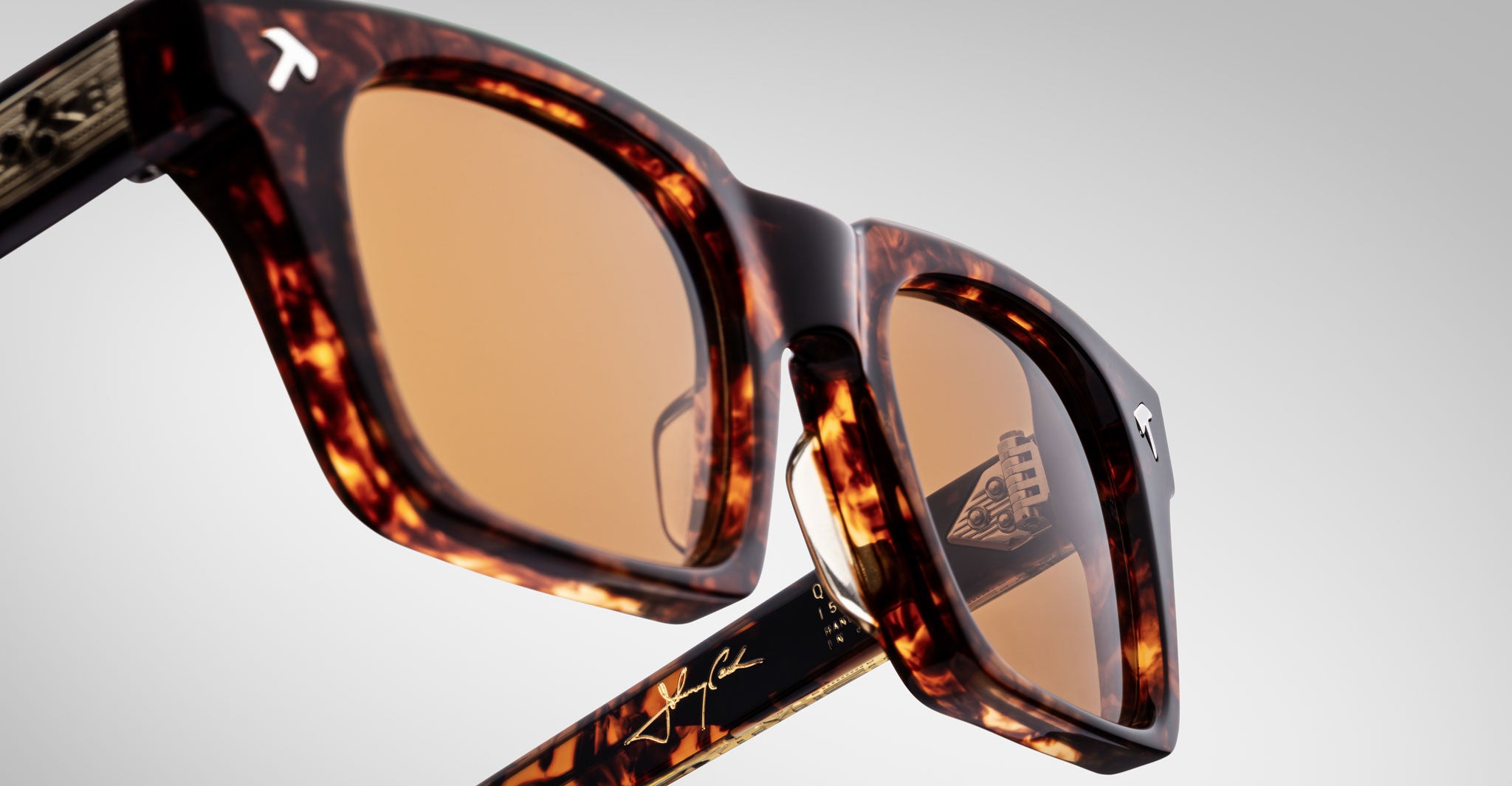 Close-up of Jacques Marie Mage Quentin sunglasses in tortoiseshell with brown lenses, brand logo, and engraved frame details.