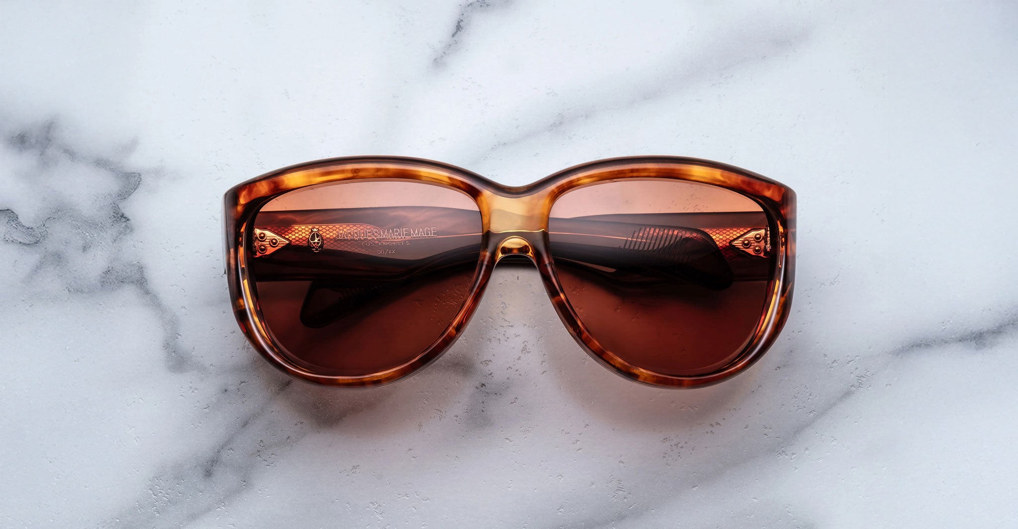 Jacques Marie Mage Ravello sunglasses featuring large, rounded brown tortoiseshell frames and dark brown lenses, displayed on a white marble surface.
