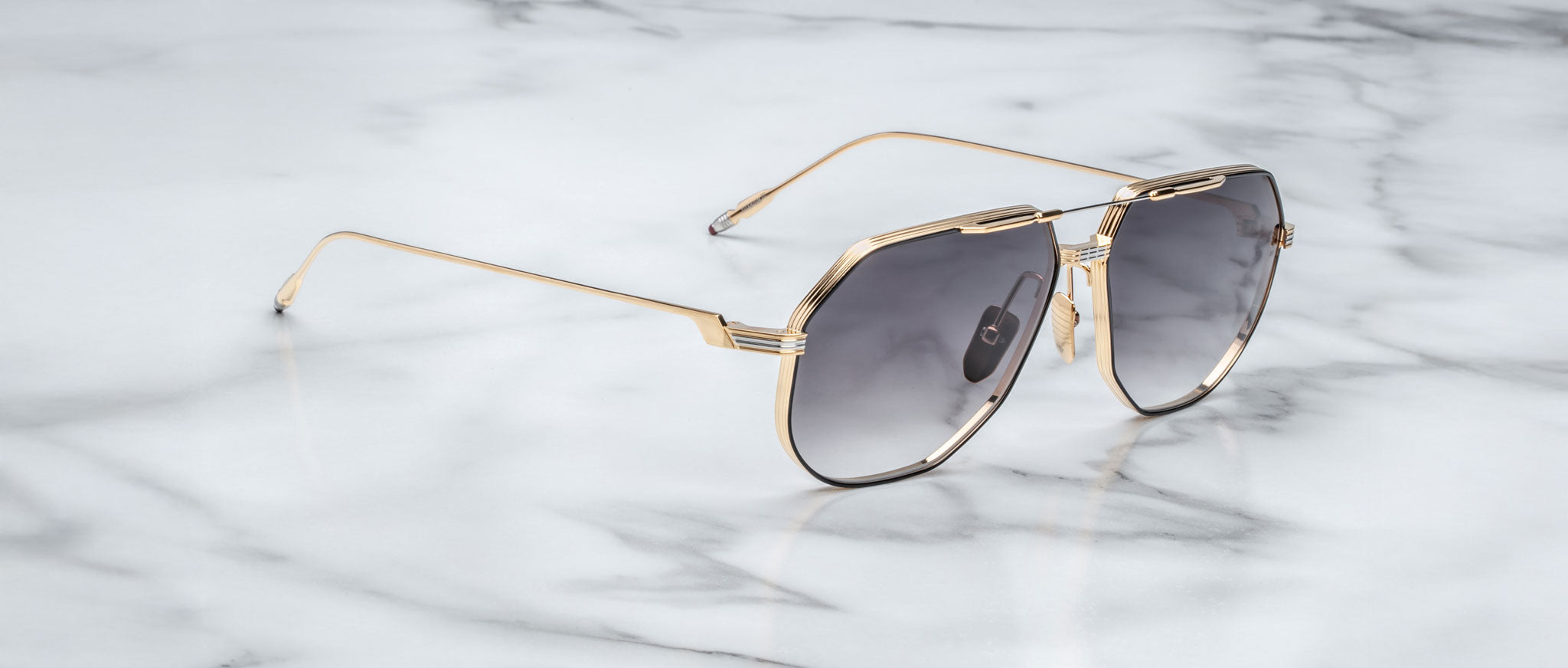 Jacques Marie Mage Reynold aviator sunglasses with gold frames and dark lenses, top view.