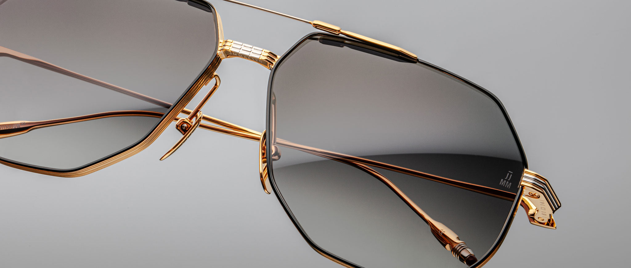 Close-up of Jacques Marie Mage Reynold sunglasses, featuring gold geometric frames and mirrored gradient lenses, front view.