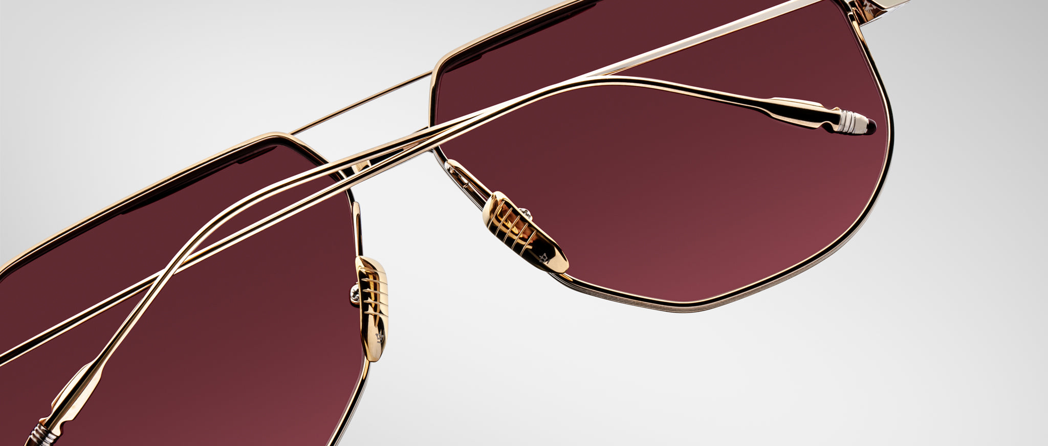 Jacques Marie Mage Reynold sunglasses with gold frames, burgundy lenses, double bridge, and adjustable nose pads, front view.