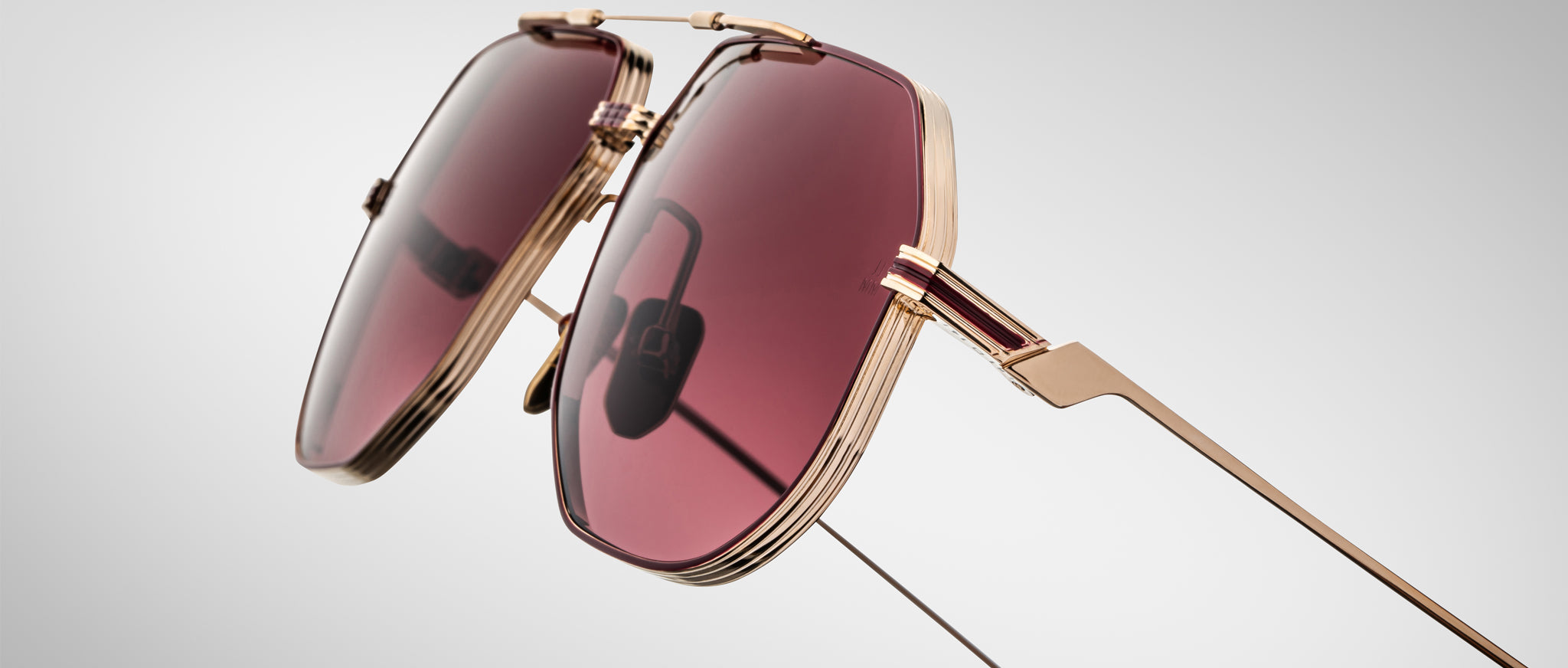 Close-up of Jacques Marie Mage Reynold gold sunglasses with pink lenses, showing the front view of the frames.