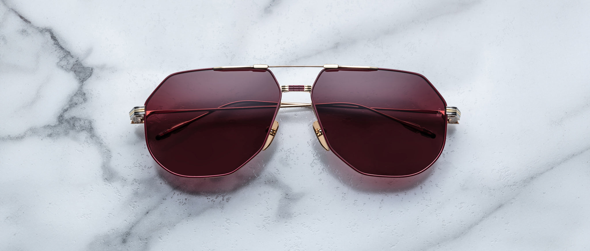 Jacques Marie Mage Reynold gold hexagonal sunglasses with dark red lenses, shown from above.