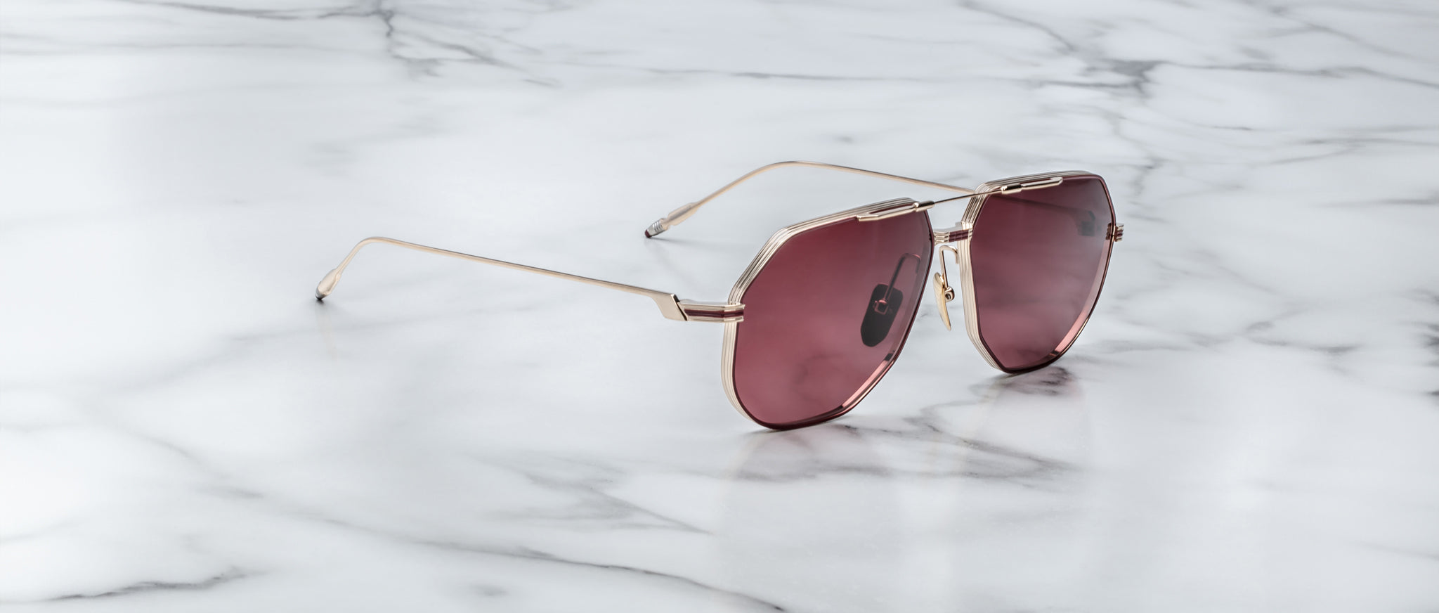 Jacques Marie Mage Reynold sunglasses with rose lenses, top-down view, showing frame and lenses on display.