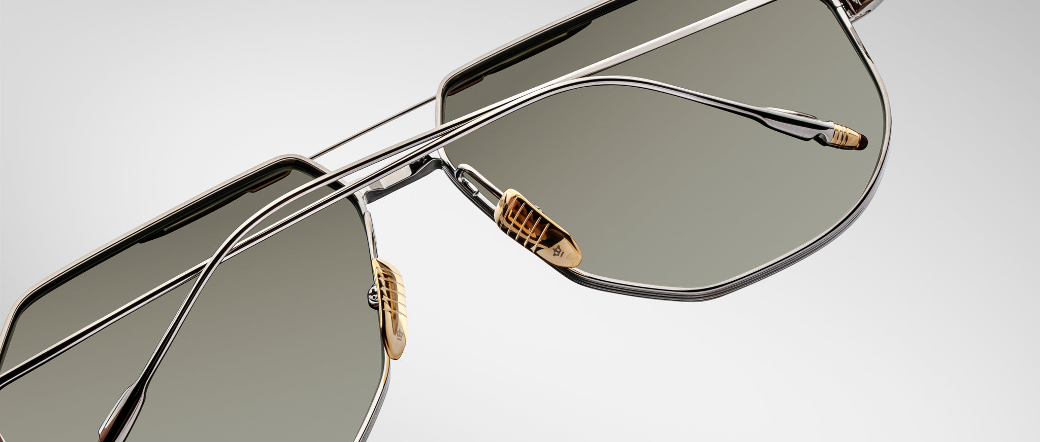 Close-up view of Jacques Marie Mage Reynold sunglasses featuring geometric metal frames, green lenses, and gold-colored temples.