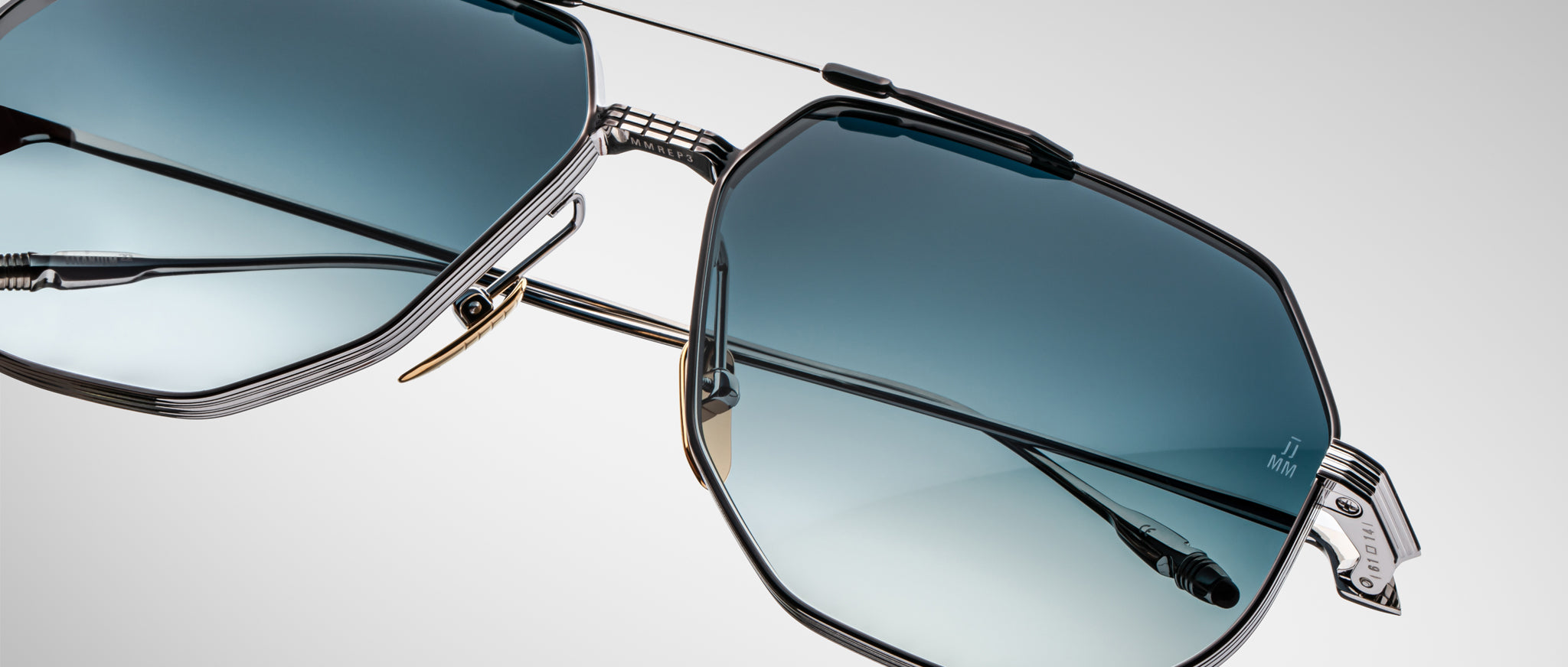 Close-up of Jacques Marie Mage Reynold sunglasses with angular metal frame and blue gradient lenses, viewed from the front.