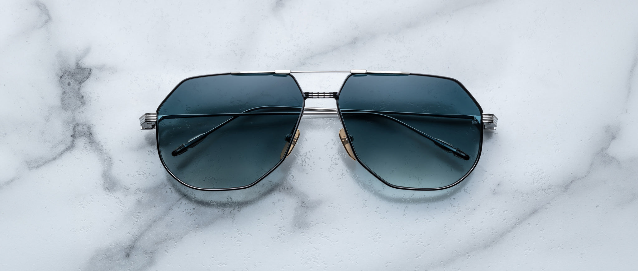 Jacques Marie Mage Reynold sunglasses with metal frames and dark lenses, shown from a top-down angle.