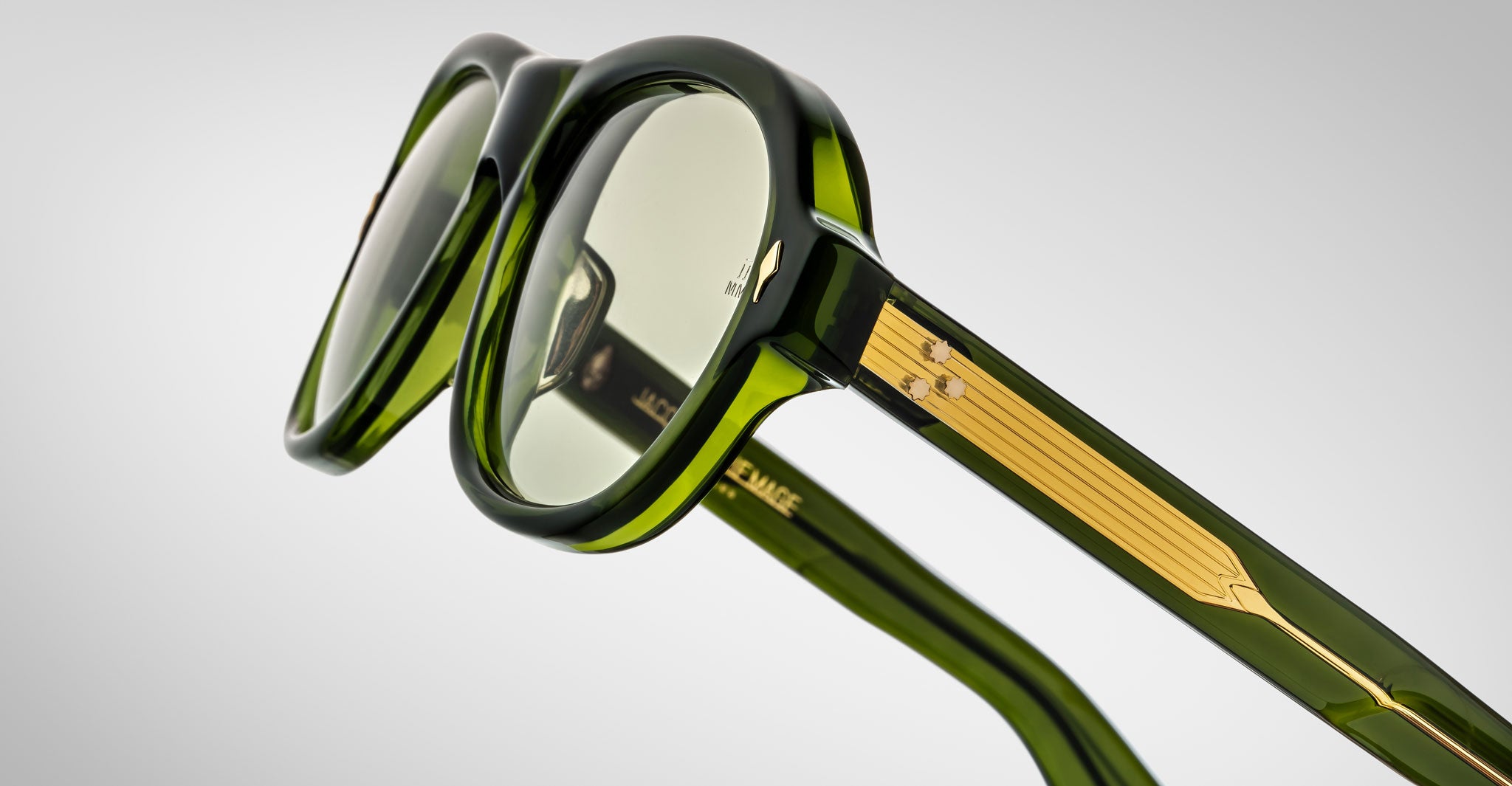 Detailed profile view of a pair of Jacques Marie Mage Richard green, thick-framed sunglasses with light green lenses on a plain background