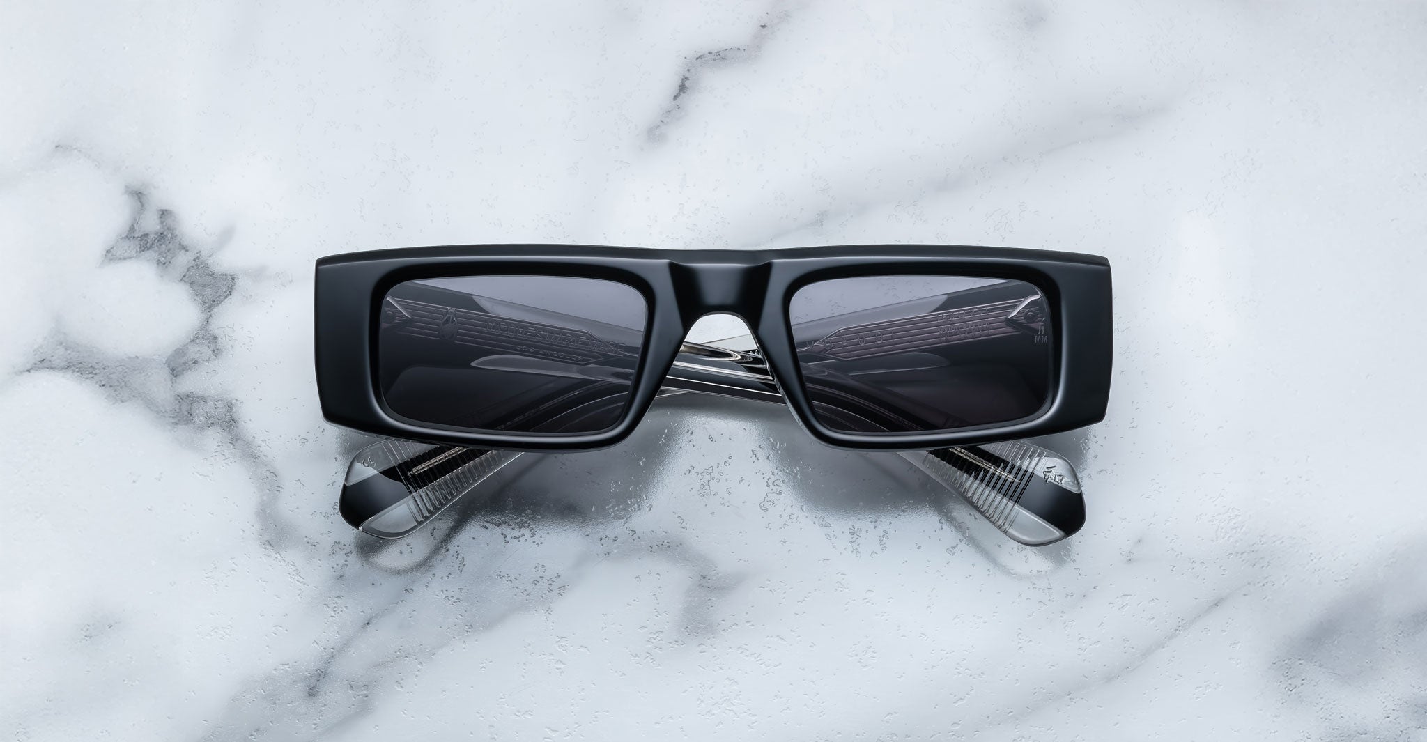 Front view of the Jacques Marie Mage Rimbaud sunglass in black color with grey lenses on a white marbled with grey veining background