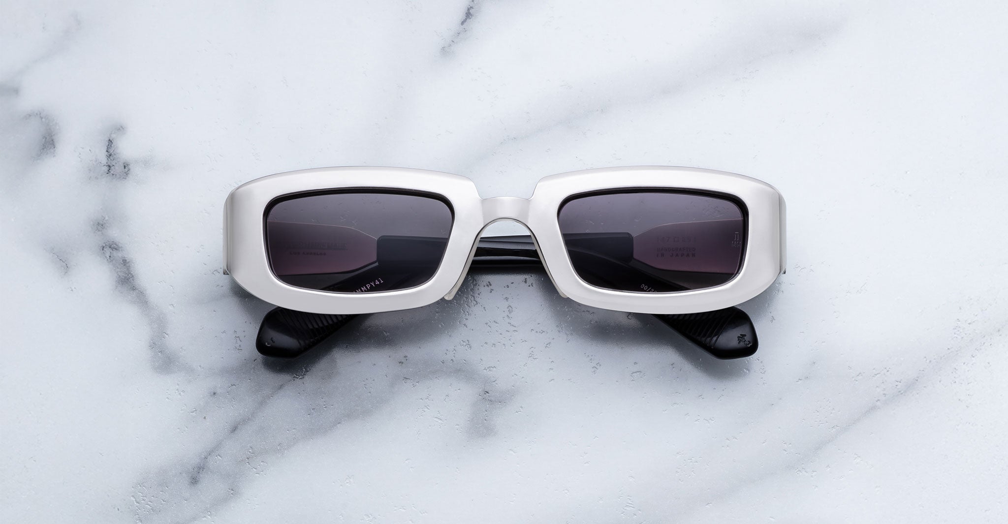 Jacques Marie Mage Ryder in Silver, rectangular silver-tone acetate sunglasses with thick sculpted rims, a low-profile bridge, and gradient tinted lenses, shown front-facing on a light marble surface.