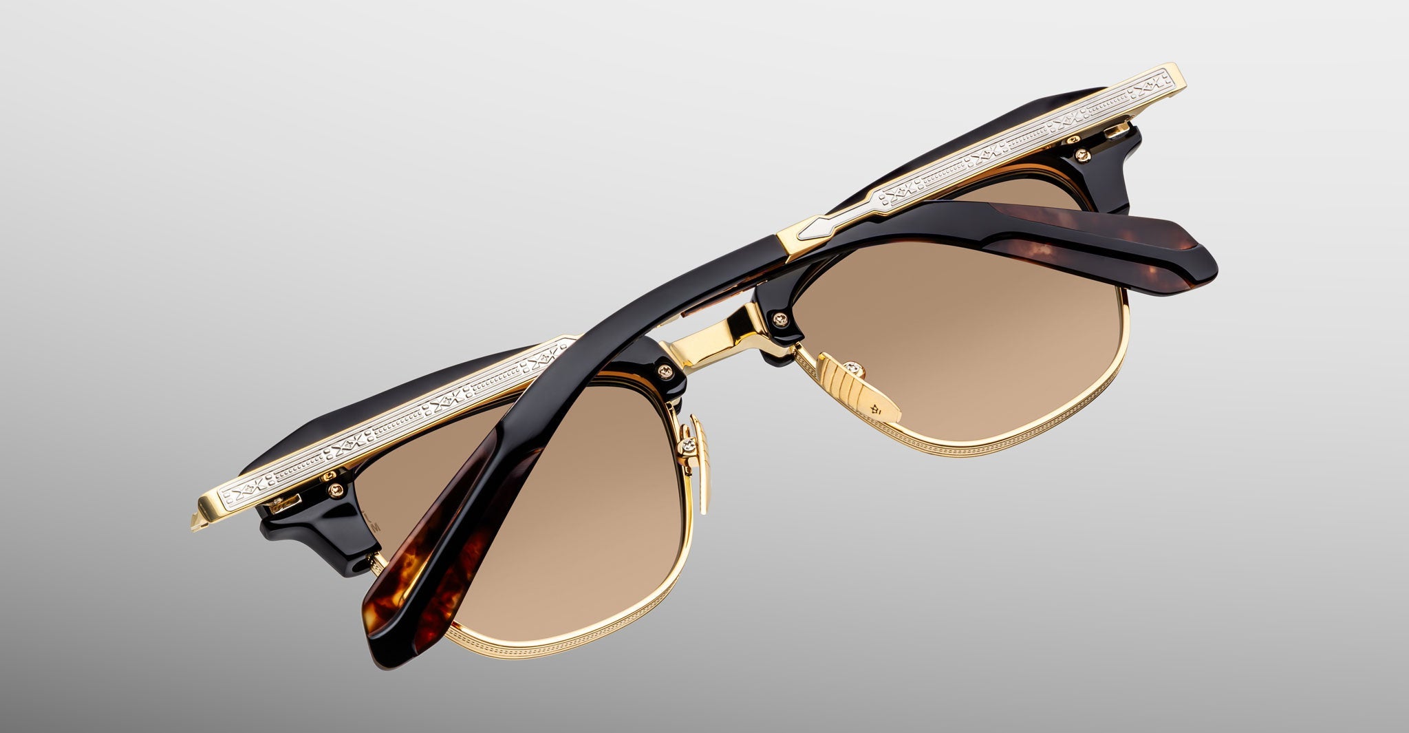 The Jacques Marie Mage Sartre sunglasses by Jacques Marie Mage feature gold and tortoiseshell frames, a titanium eye rim, brown tinted lenses, and ornate temple detailing for a refined finish.