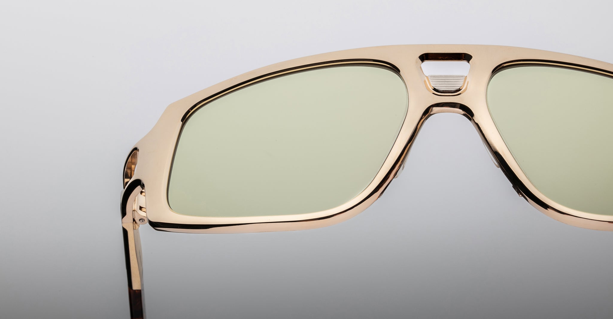 Close-up of Jacques Marie Mage Scarface sunglasses with gold frames and green-tinted lenses, product seen from the front.