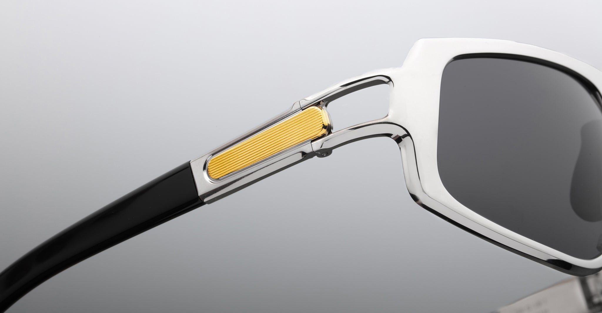 Close-up of Jacques Marie Mage Scarface sunglasses showing silver frame, black arms, and gold hinge accent, side view.