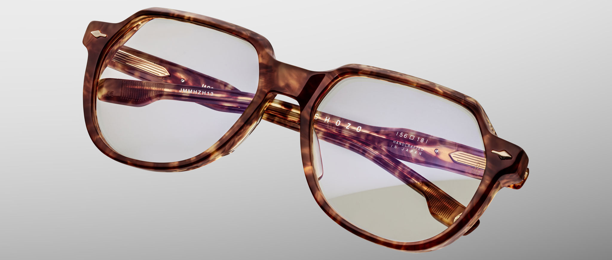 The Jacques Marie Mage Shozo is a pair of stylish, square-shaped eyeglasses with tortoiseshell frames and clear lenses, shown against a plain light gray background. The temples feature distinct detailing and engraved text.