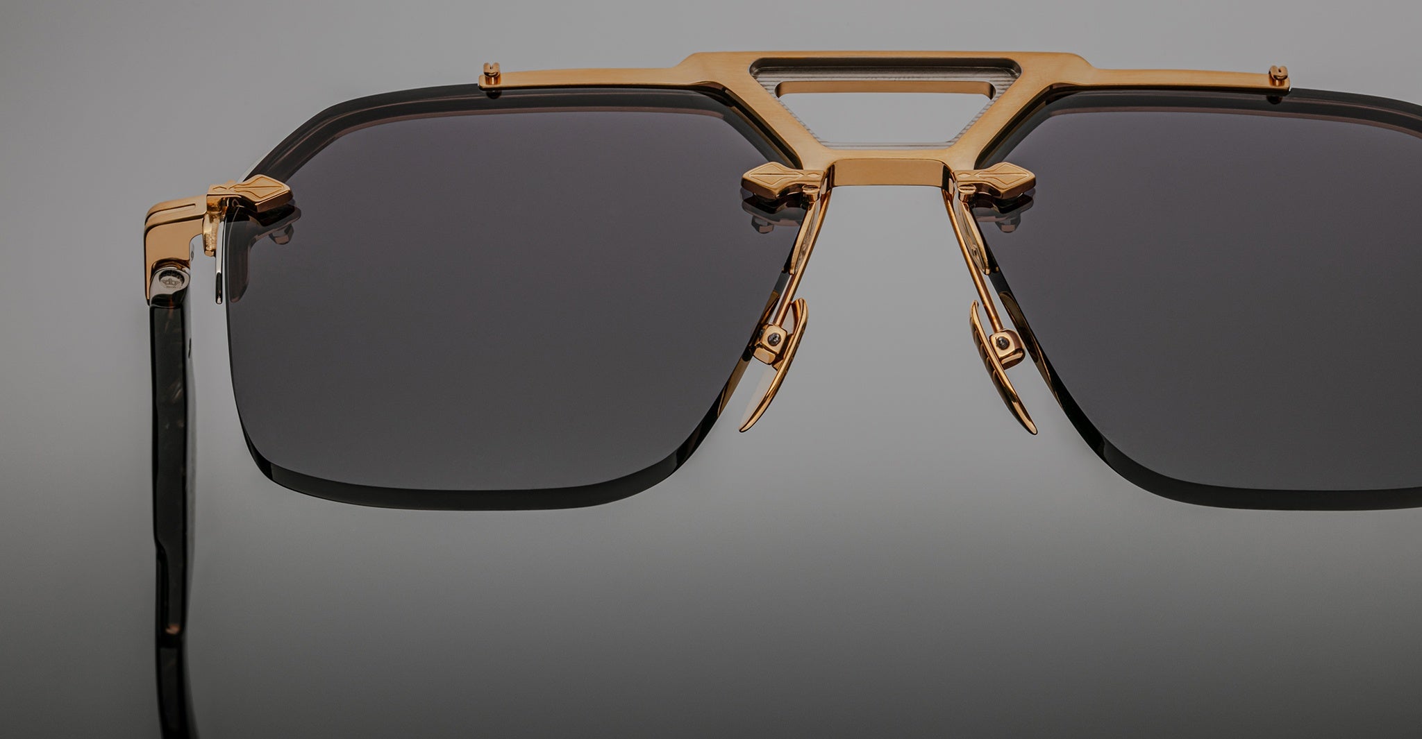 Close-up of Jacques Marie Mage Silverton sunglasses, featuring dark lenses and an intricate gold metal geometric frame with decorative accents above the nose bridge.