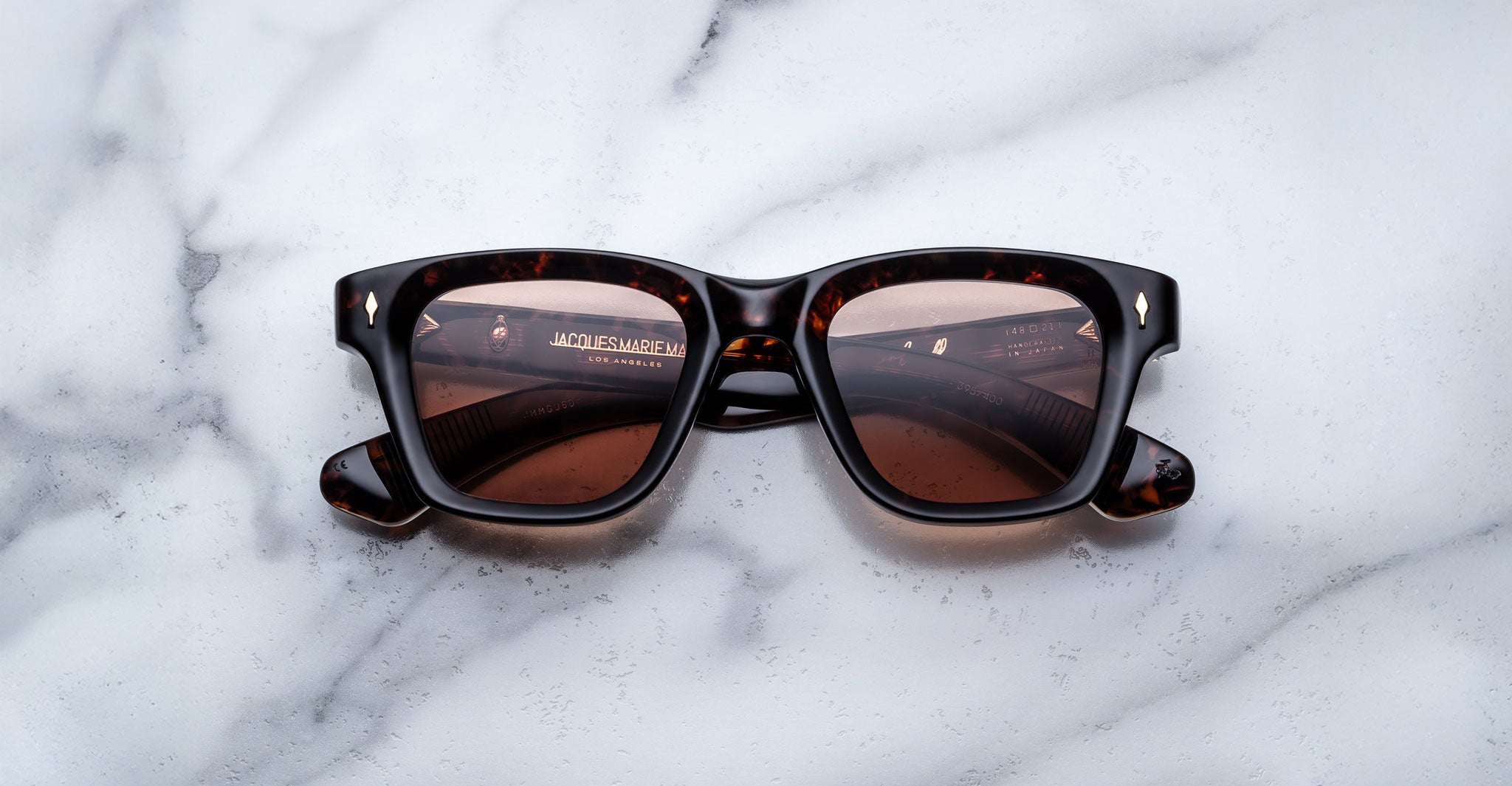 Jacques Marie Mage Sonata tortoiseshell rectangular sunglasses with brown lenses shown from above on a flat surface.