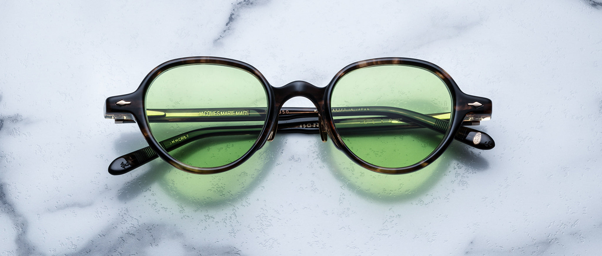 Jacques Marie Mage The Clark eyeglasses feature green tinted lenses and dark frames, shown from above.