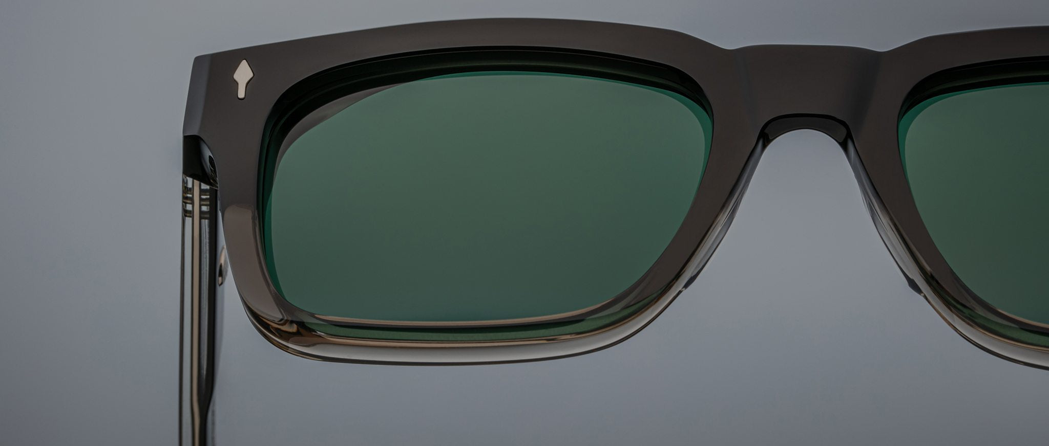 Close-up of the Jacques Marie Mage Torino sunglasses by Jacques Marie Mage, featuring bold rectangular black handcrafted acetate frames with dark green lenses against a plain background.