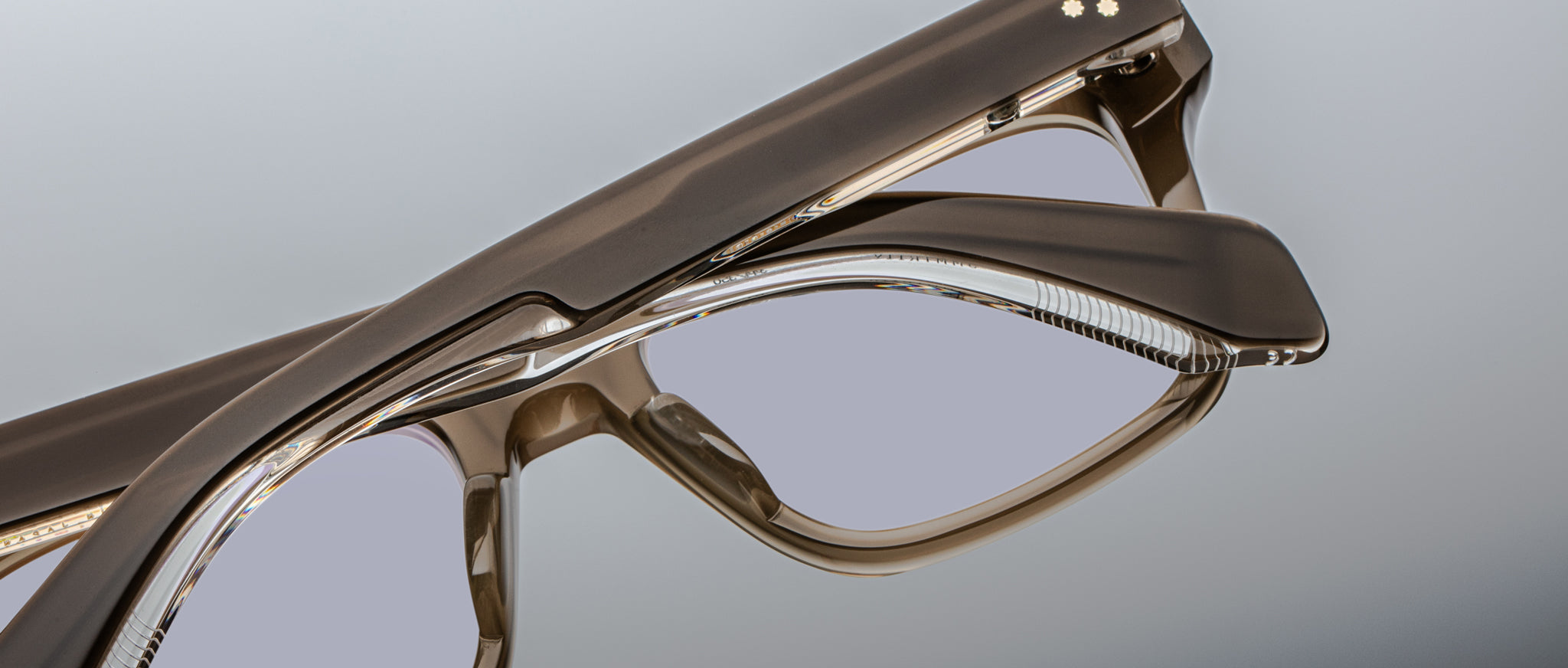 Close-up of Jacques Marie Mage Torino eyeglasses by Jacques Marie Mage, showcasing bold rectangular frames in glossy handcrafted acetate with clear lenses, displayed against a neutral background.