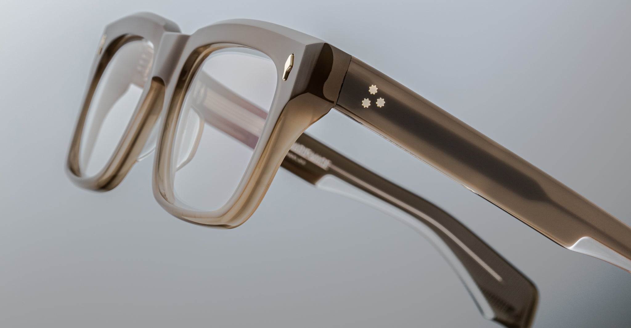 Close-up of Jacques Marie Mage Torino eyeglasses: bold rectangular frames in transparent handcrafted acetate with thick temples and two decorative dots, showcasing Jacques Marie Mage’s distinctive style.