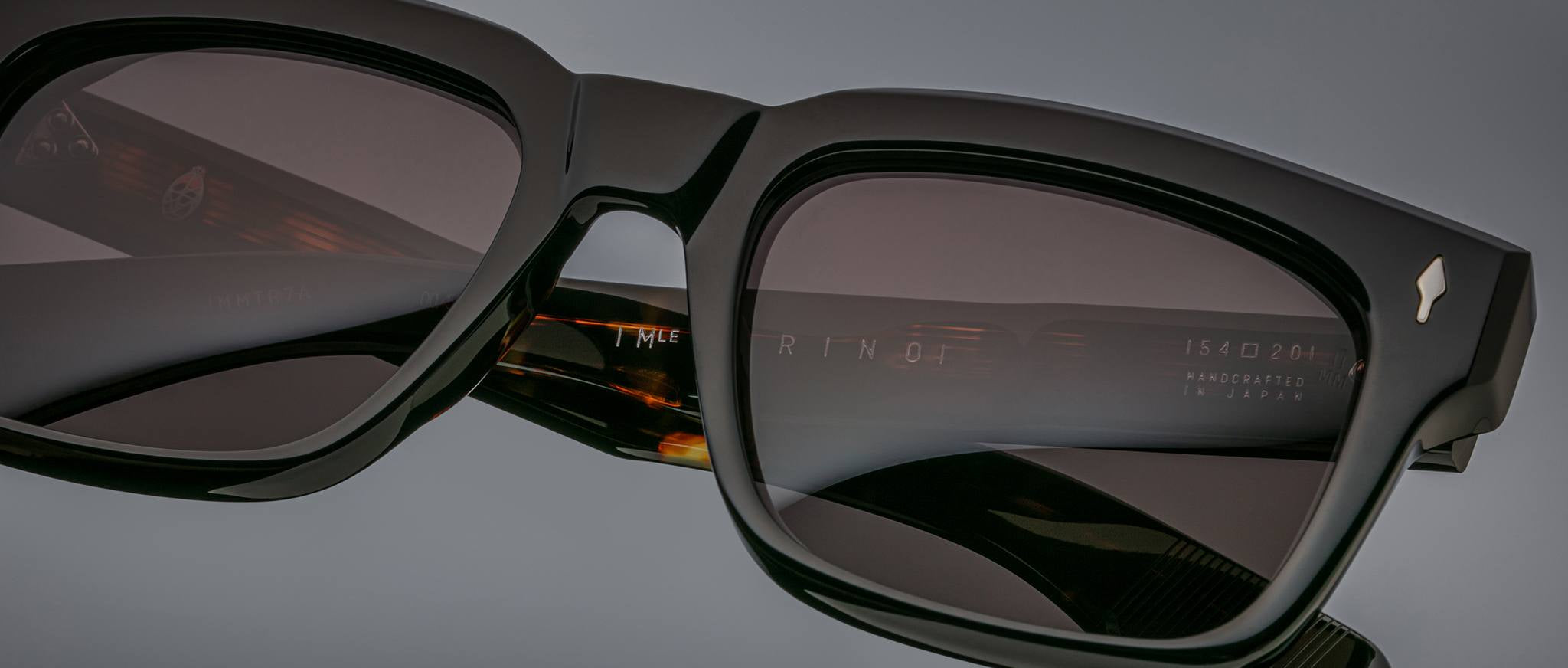 Close-up of Jacques Marie Mage Torino bold rectangular black acetate frames, featuring dark lenses and “Handcrafted in Japan” on the inner arm, highlighting the brand's exquisite craftsmanship.