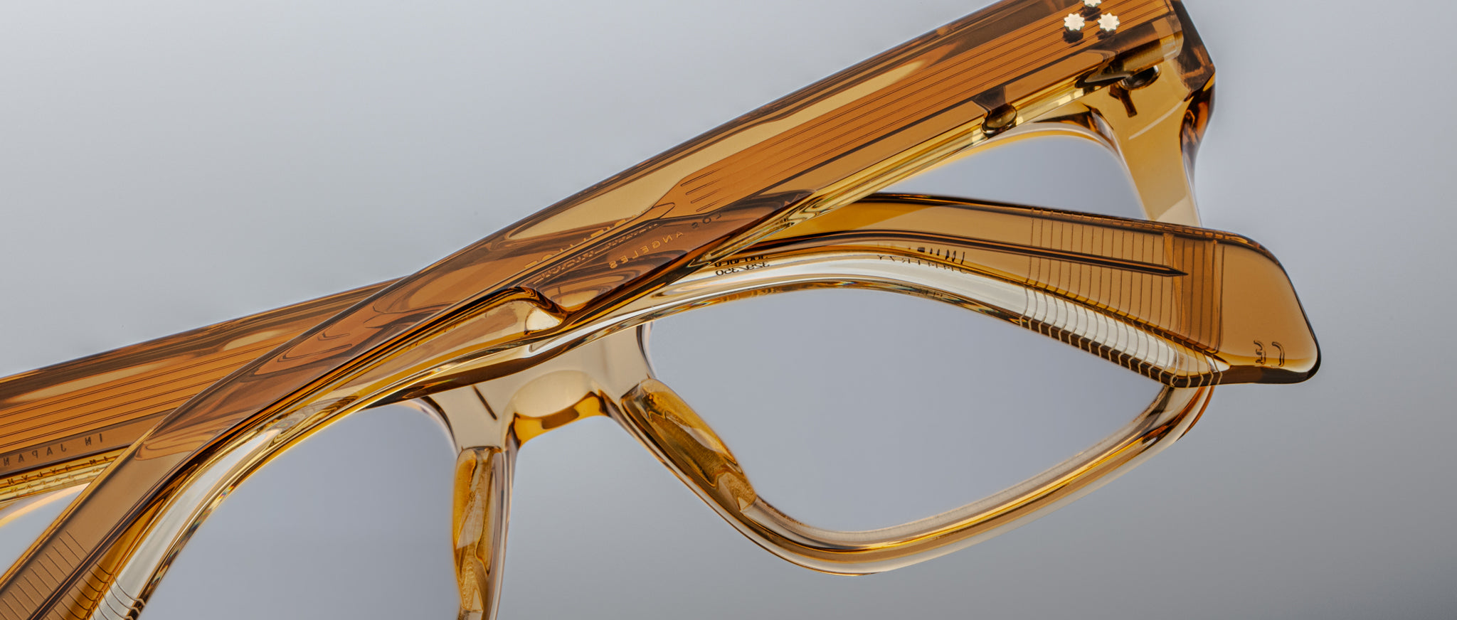 Close-up of two pairs of Jacques Marie Mage Torino eyeglass frames, featuring bold rectangular shapes and handcrafted acetate, stacked together against a plain background.