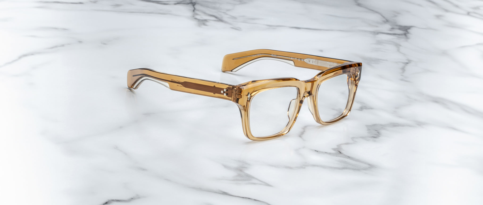 The Jacques Marie Mage Torino, bold rectangular eyeglass frames by Jacques Marie Mage, are crafted from translucent brown handcrafted acetate and displayed on a white marble surface.